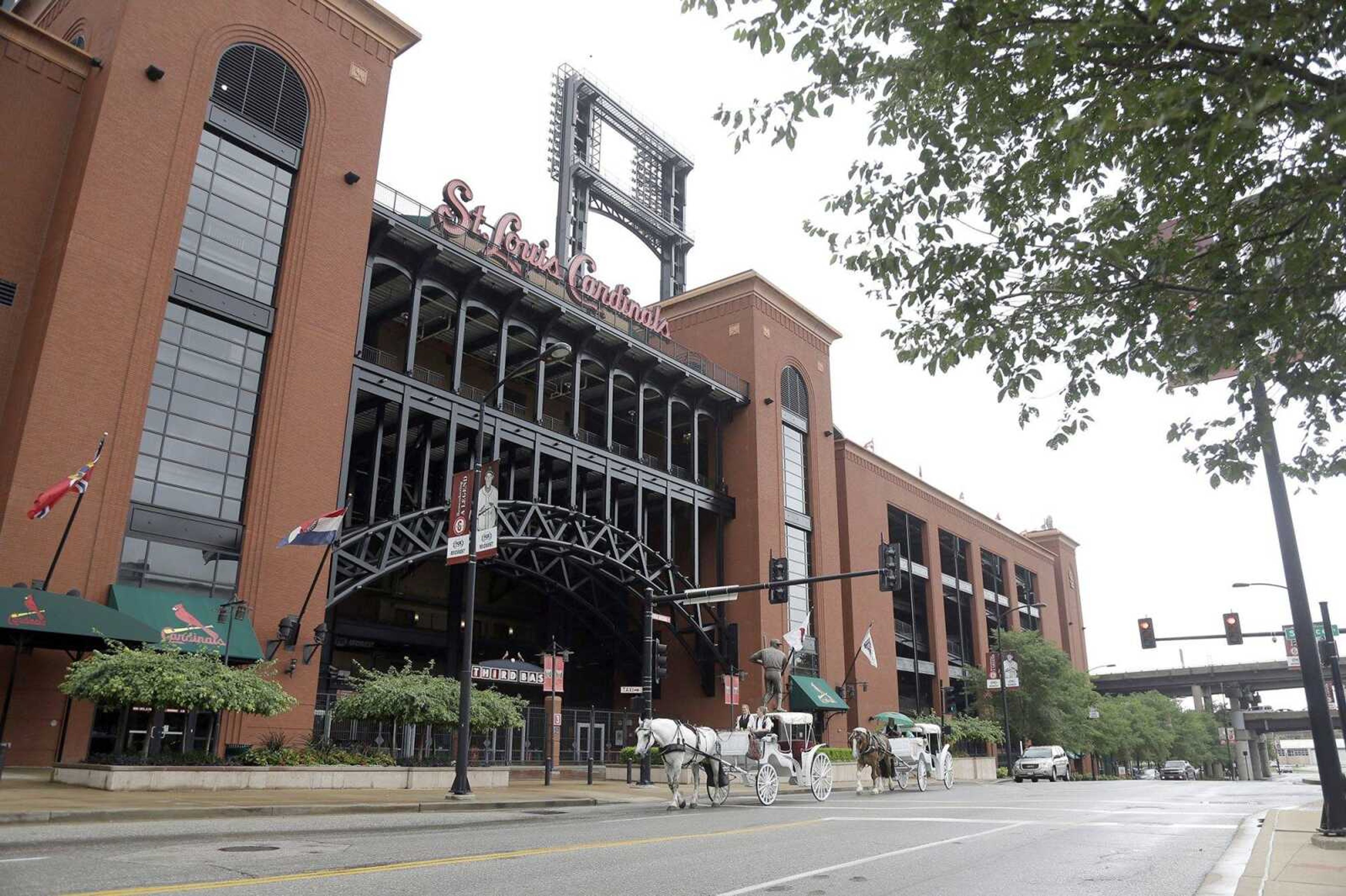 Horse-drawn carriages pass Busch Stadium, the home of the St. Louis Cardinals baseball team, Wednesday, June 17, 2015, in St. Louis. The team said Wednesday it hired a law firm several months ago to conduct an internal inquiry and to assist the FBI and Justice Department in their investigation into possible computer hacking of the Houston Astros database by members of the Cardinals organization. (AP Photo/Jeff Roberson)