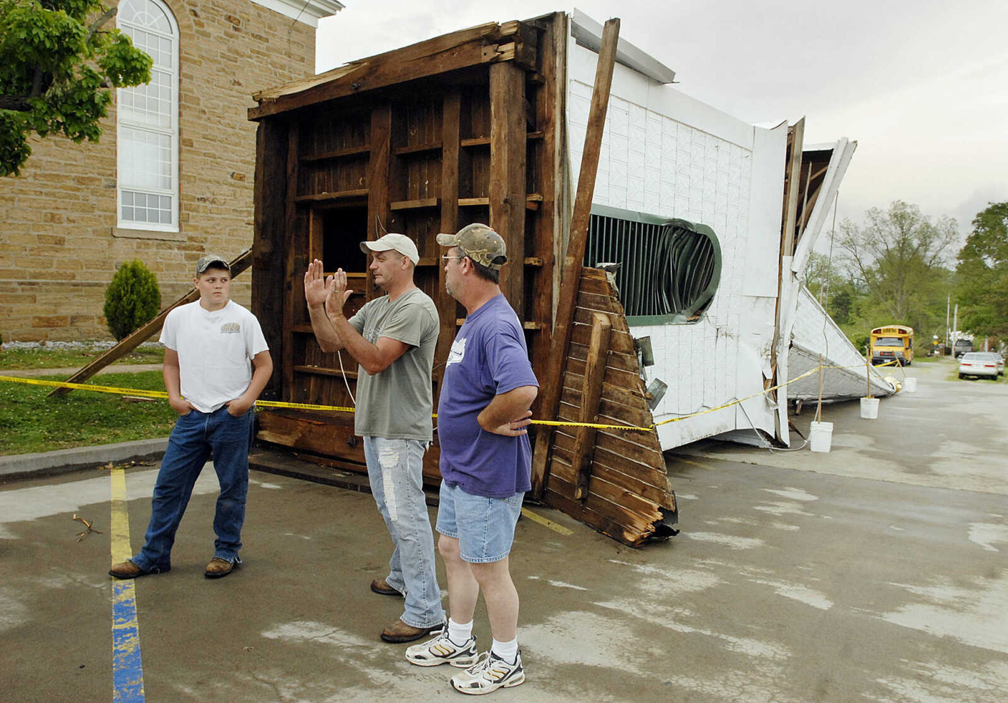 ELIZABETH DODD ~ edodd@semissourian.com
Members of Trinity Lutheran Church Aaron Hadler, left, Stan Hadler and Steve Hadler of Altenburg discuss plans for dealing with the damage Wednesday from May 8 storms next to the 142 year old steeple that was blown over from wind and carefully removed with a crane so the roof would not cave in.