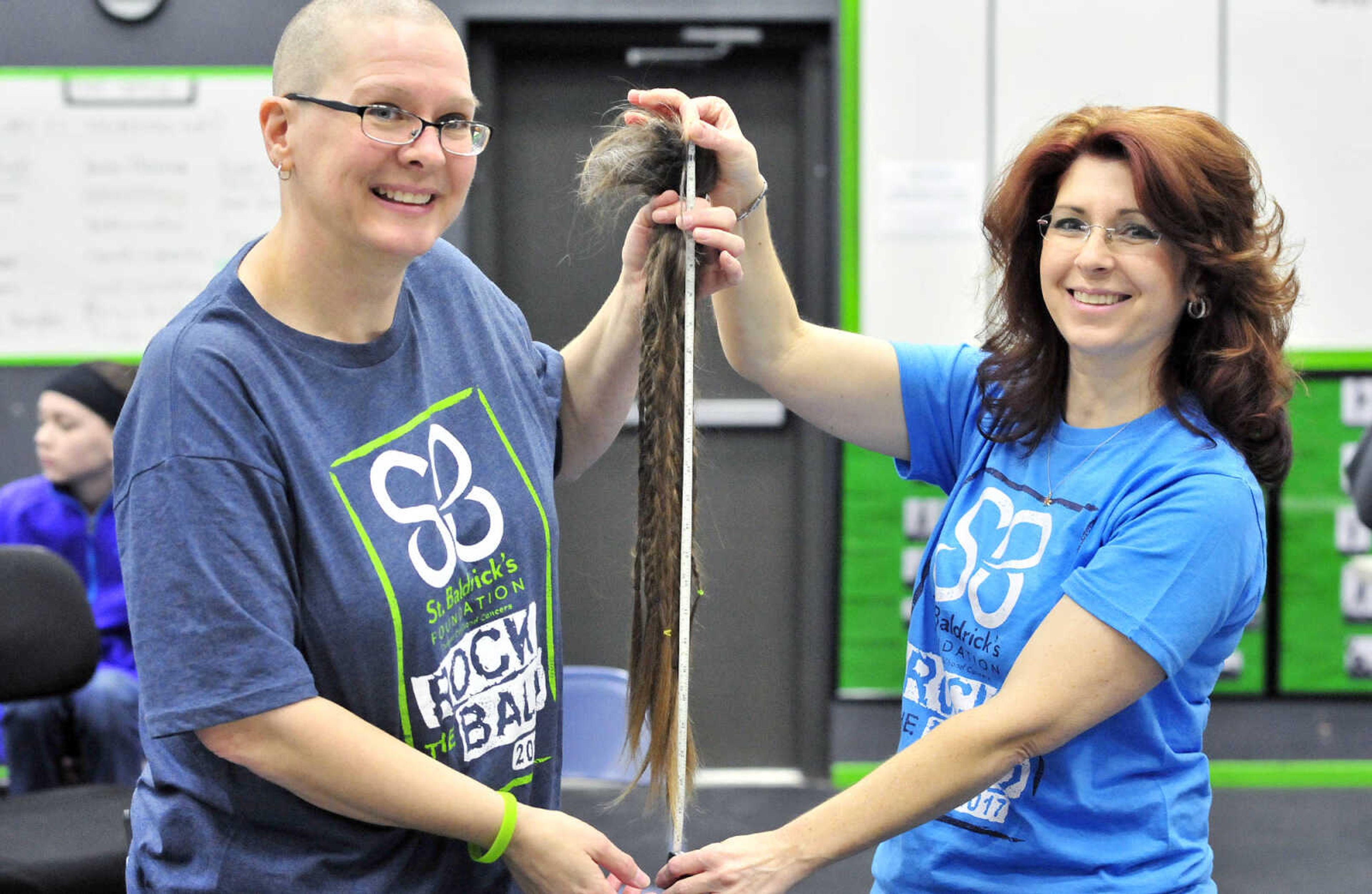 Jennifer Singleton, left, and April Whiteside hold Singleton's 25-26 inches of her hair she had shaved off on Saturday, March 4, 2017, during the St. Baldrick's Foundation fundraiser at Old Orchard CrossFit in Jackson.