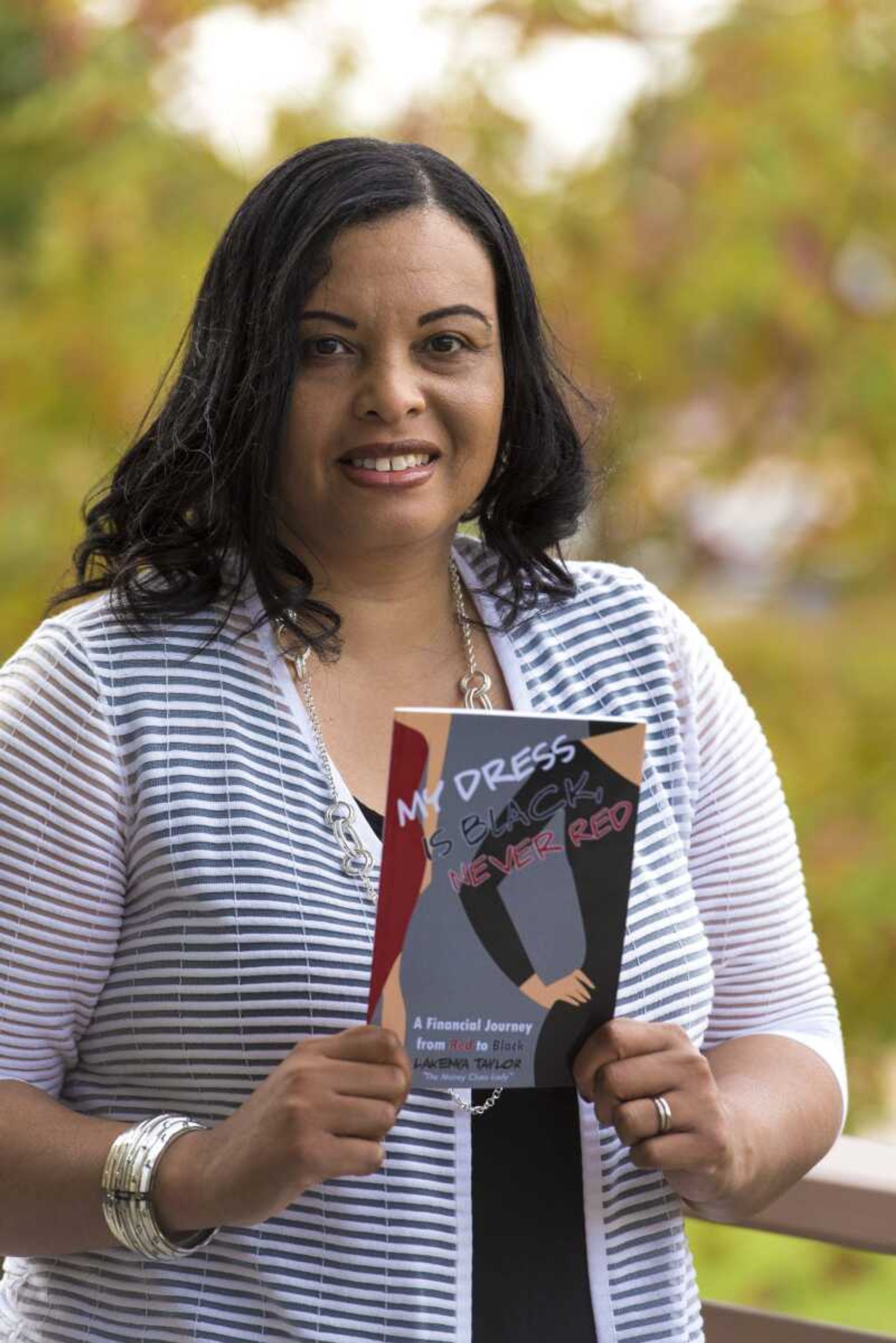 Cutline Email/Stock:PHOTO BY ANDREW J.Cutline Email/Stock:WHITAKERCutline Email/Stock:LaKenya Taylor poses with her book "My Dress is Black, Never Red"at the Cape Girardeau Public Library. Taylor is also the creator of Pad It, a program that provides feminine products to girls at local public schools.