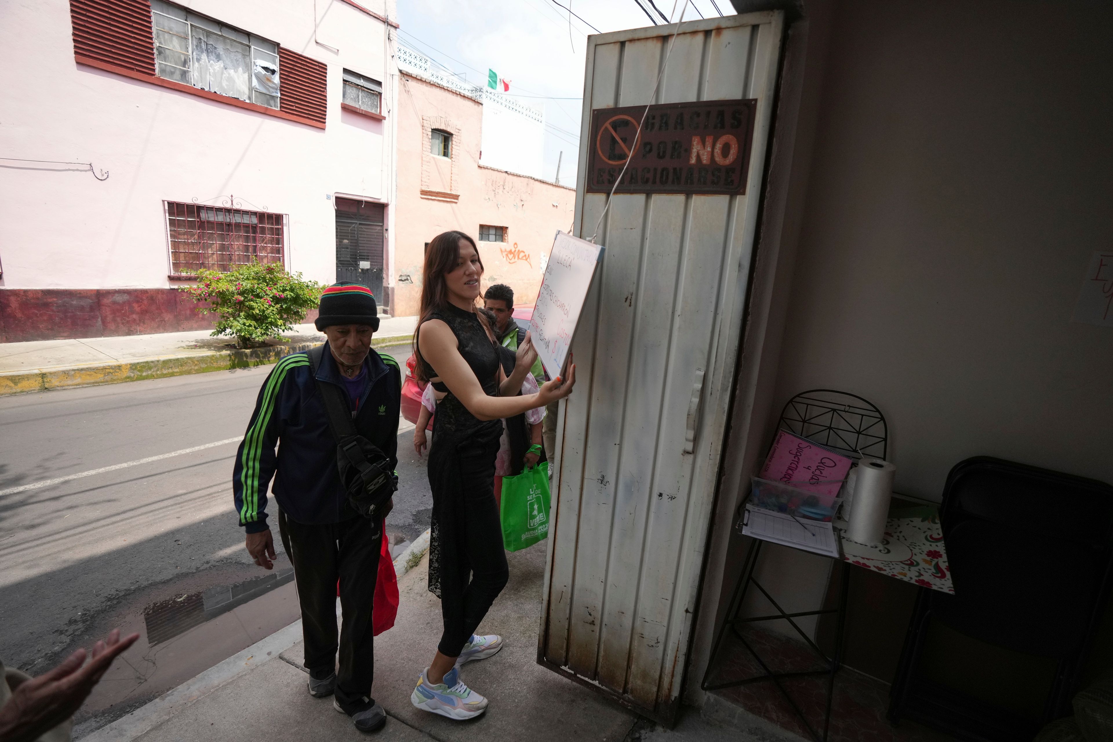 Victoria Sámano adjusts a menu while opening the community kitchen at Casa Lleca, an LGBTQ+ shelter in the Peralvillo neighborhood of Mexico City, Friday, Sept. 20, 2024. Sámano, a trans woman, founded the shelter in 2020 in an effort to help LGBTQ+ people and sex workers who were unhoused or at risk of losing their homes. (AP Photo/Fernando Llano)