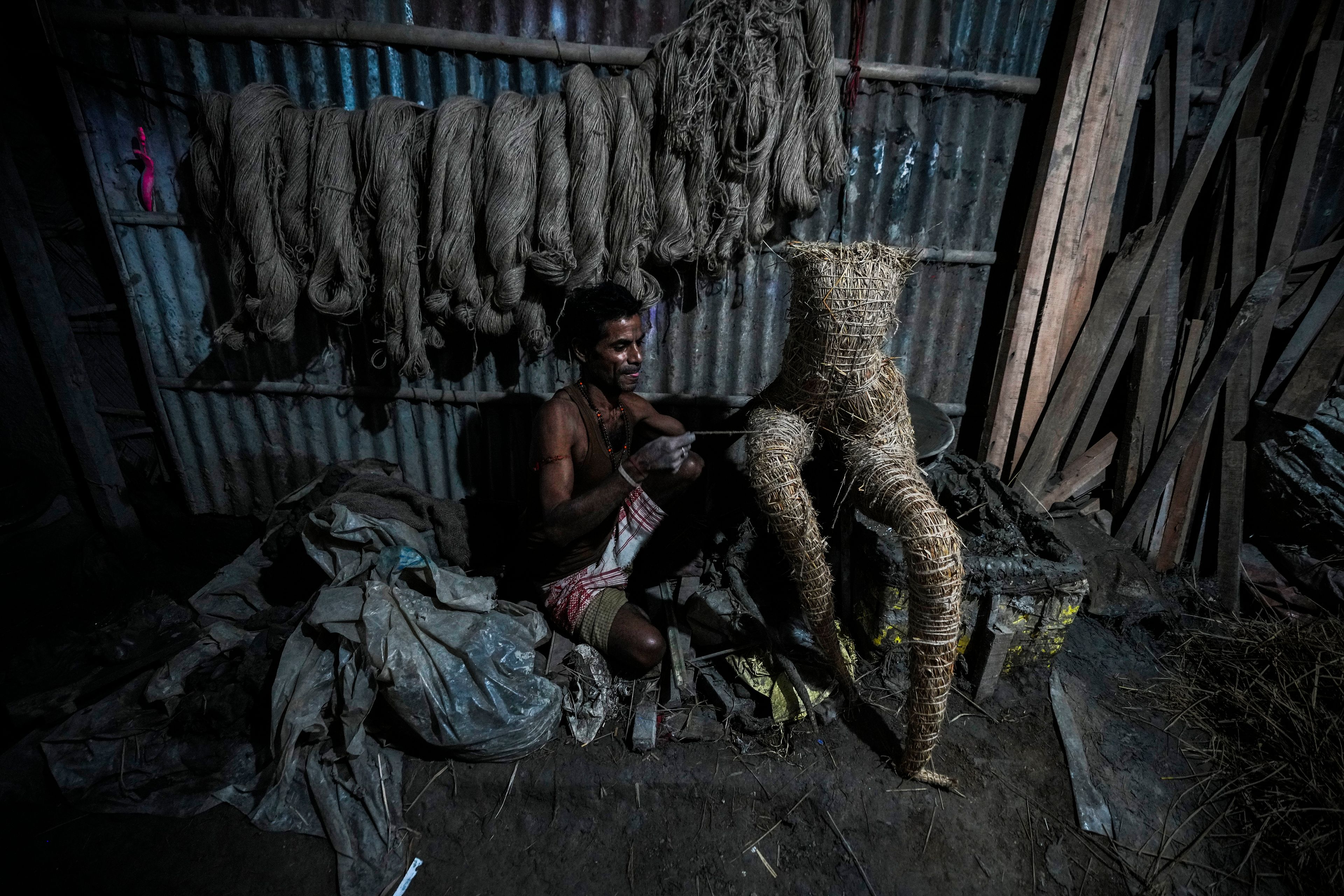 An artisan uses bamboo, hay and ropes to make a skeleton for the construction of a mud idol of the Hindu goddess Durga at a workshop during the Durga Puja festival in Guwahati, India, Friday, Oct. 4, 2024. (AP Photo/Anupam Nath)