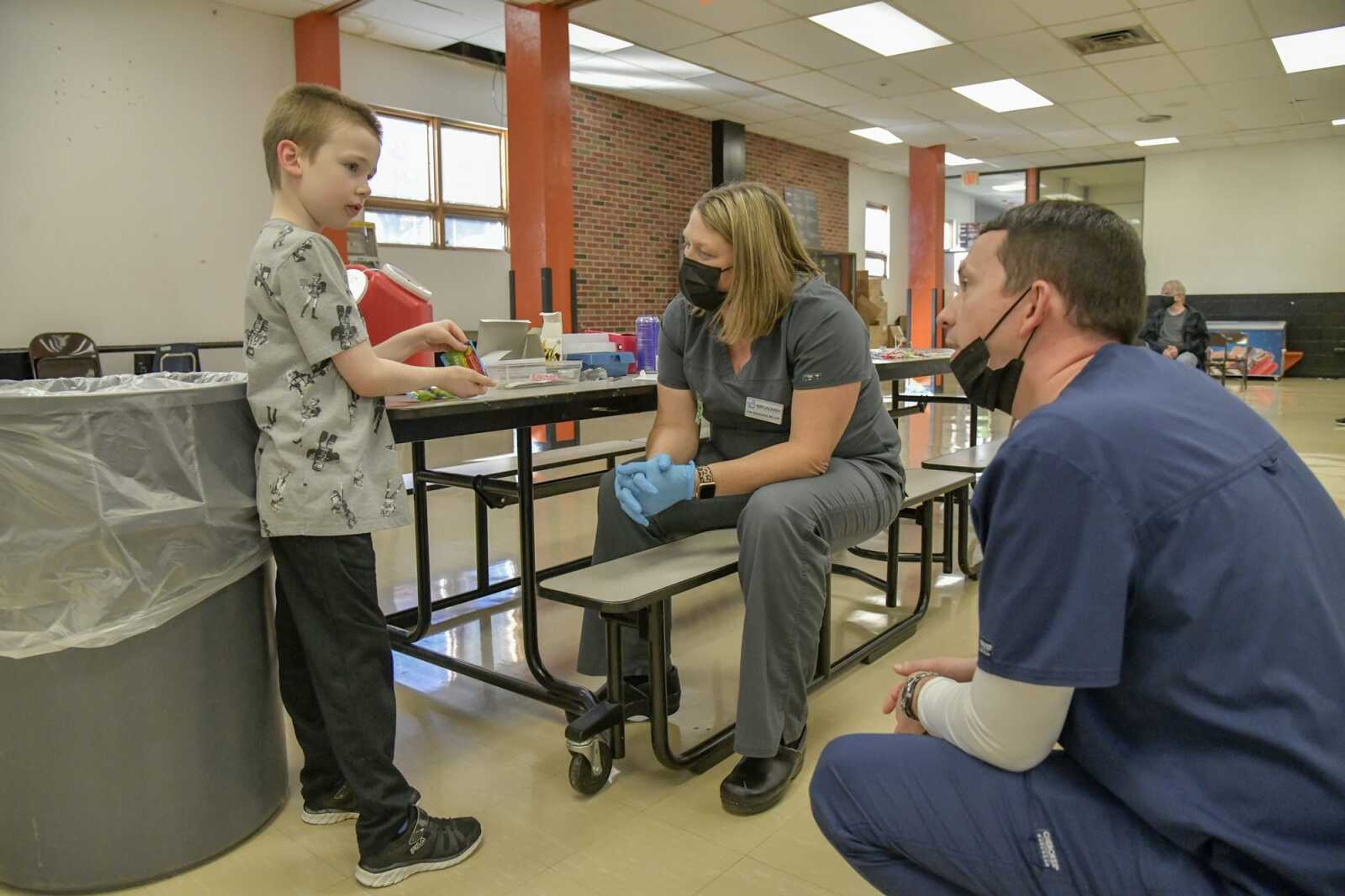 Jayce Lewis, 7, who was nervous about the needle, talks to John's Pharmacy pharmacist Abe Funk, right, and Broadway Pharmacy employee Julie Schoolfield before receiving his first COVID vaccine dose during a clinic Thursday at Cape Girardeau Central Middle School.