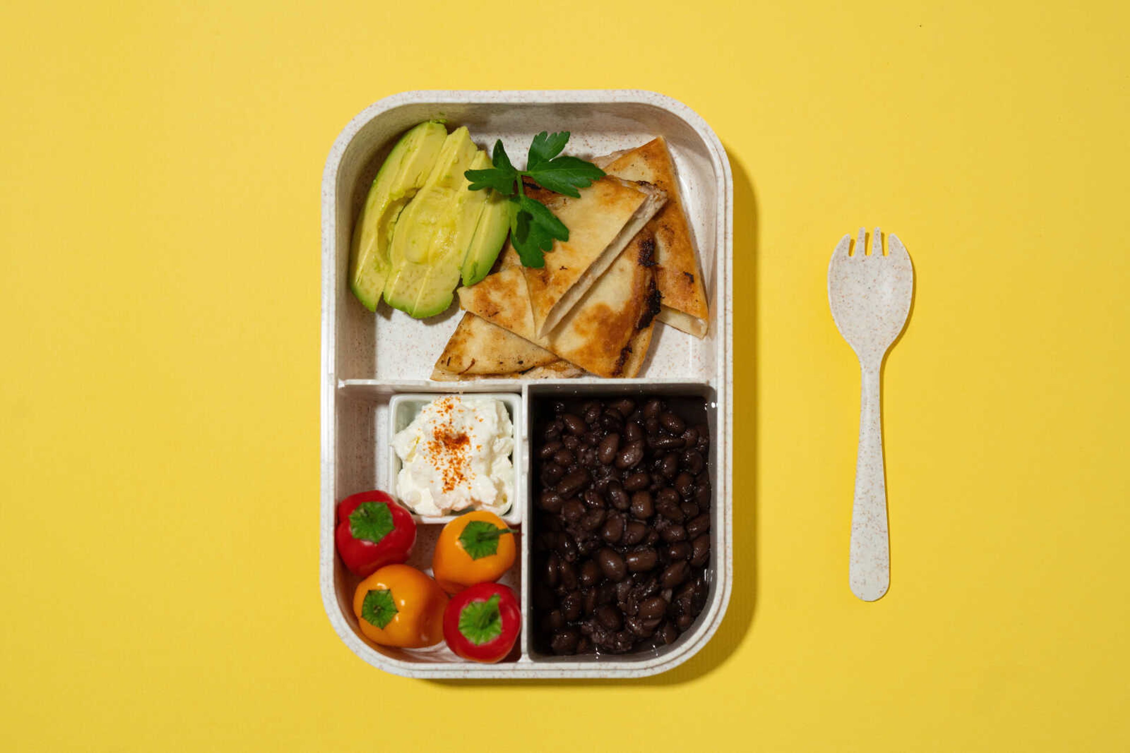 Tuna quesadillas, avocado, peppers, beans and Greek yogurt prepared by Ellen Gipson, MA, RDN, LD, are arranged in a bento box. Traditional Japanese-style bento boxes include rice, meat or fish, and a pickled vegetable.