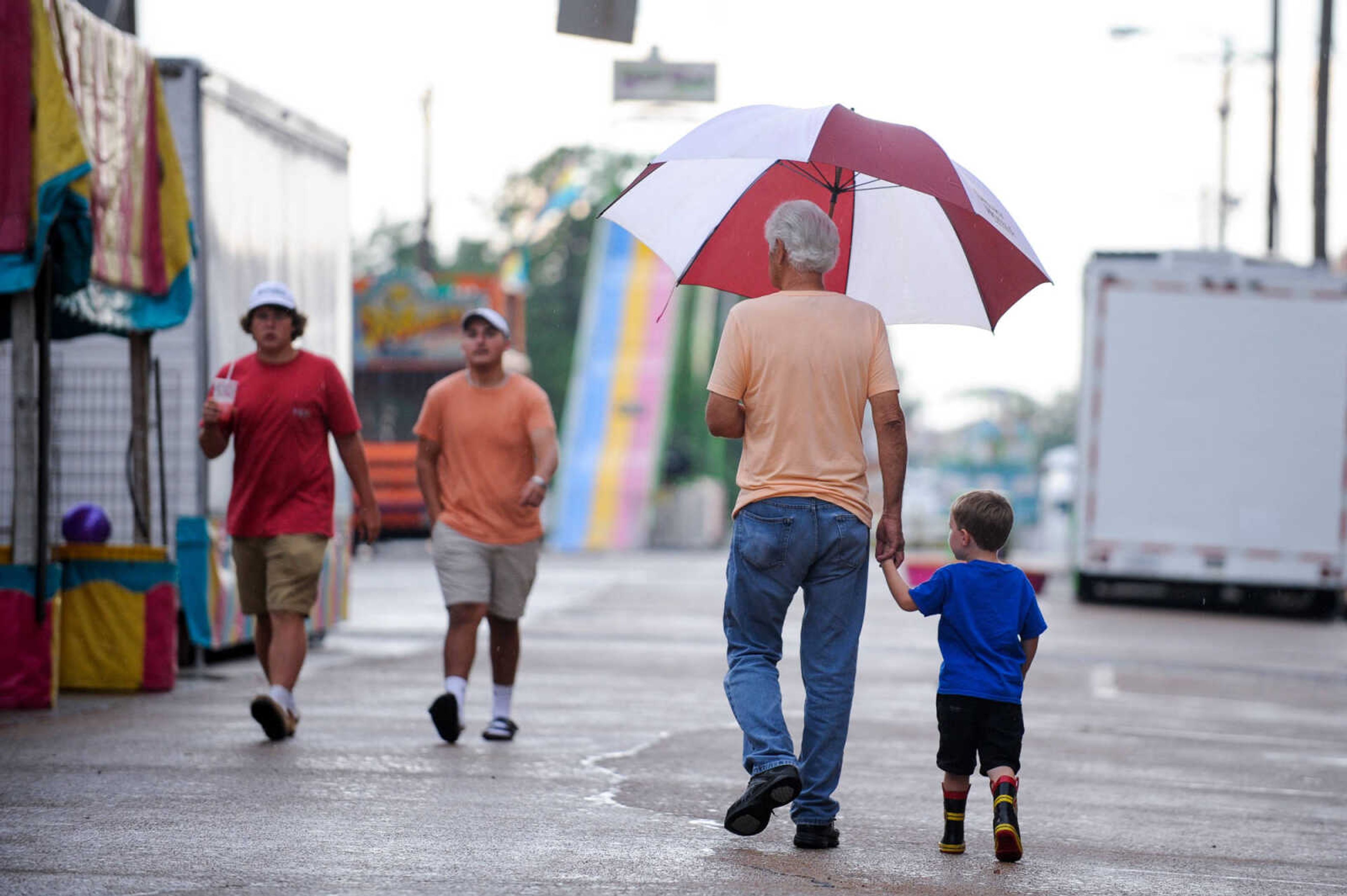 GLENN LANDBERG ~ glandberg@semissourian.com

Charles Kohler walks with his grandson, Mason Lekki, during a soggy opening day of the 108th Homecomers in Jackson, Tuesday, July 26, 2016. Homecomers runs through Saturday in uptown Jackson.