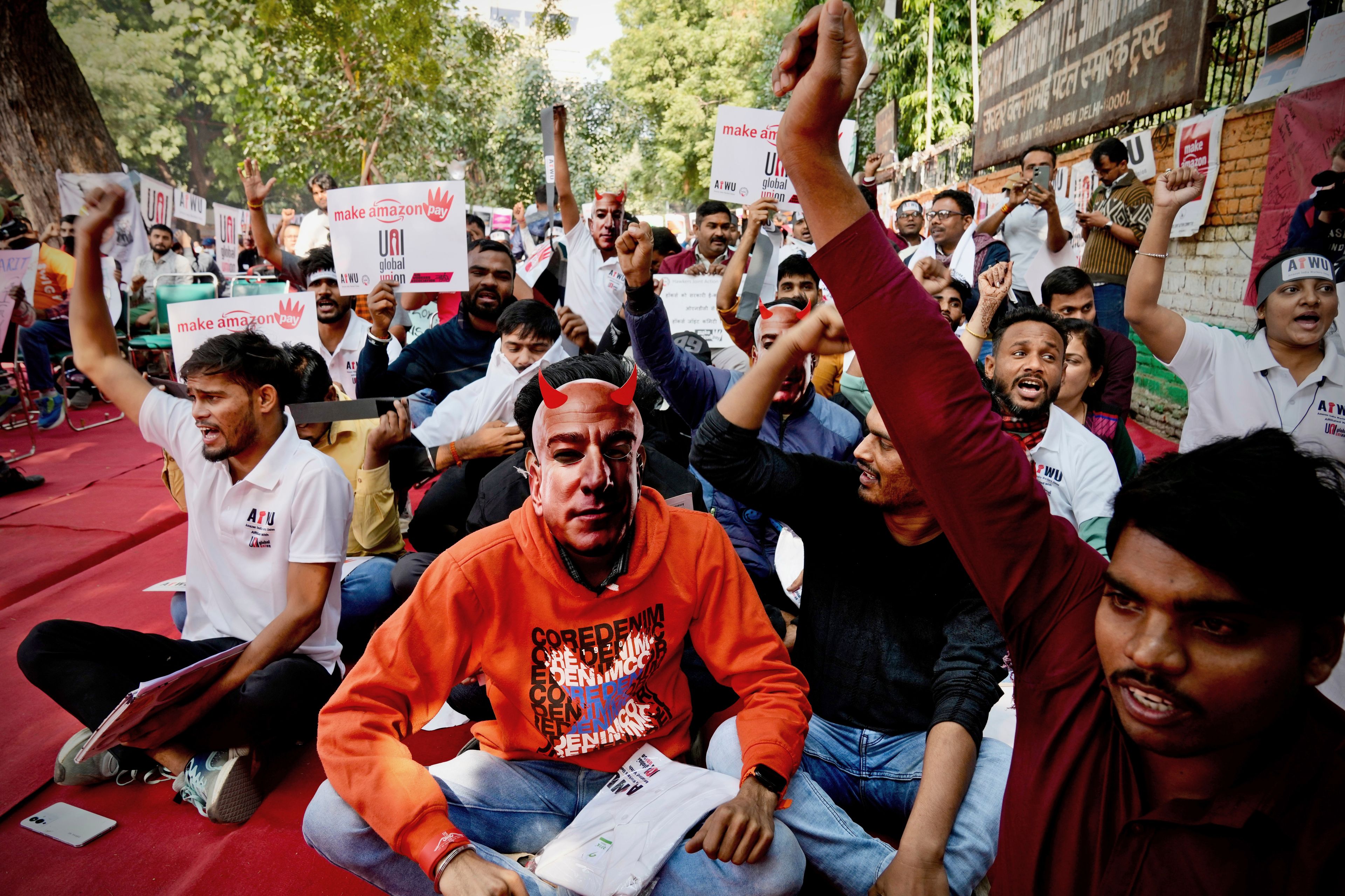 A participant wears a paper mask in the likeness of Amazon's Jeff Bezos as warehouse workers and delivery drivers stage a protest against the Seattle-based company demanding higher wages and better working conditions, in New Delhi, India, Friday, Nov. 29, 2024. (AP Photo/Manish Swarup)