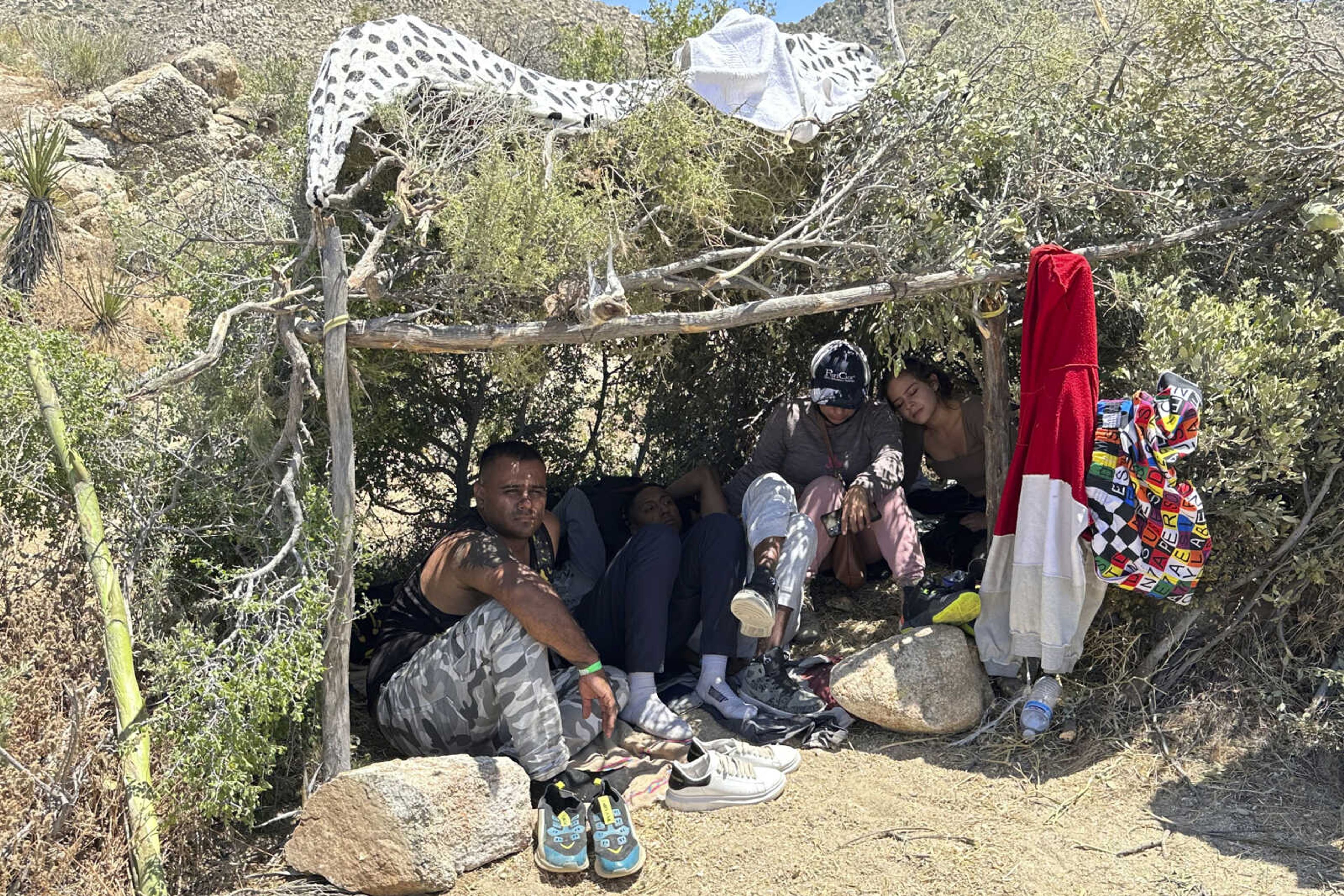 Colombian migrants gather in a self-made shade made of branches while waiting to be processed by the U.S. Border Patrol agents Saturday near the Jacumba Hot Springs, an unincorporated community in the Mountain Empire area of southeastern San Diego County, California.