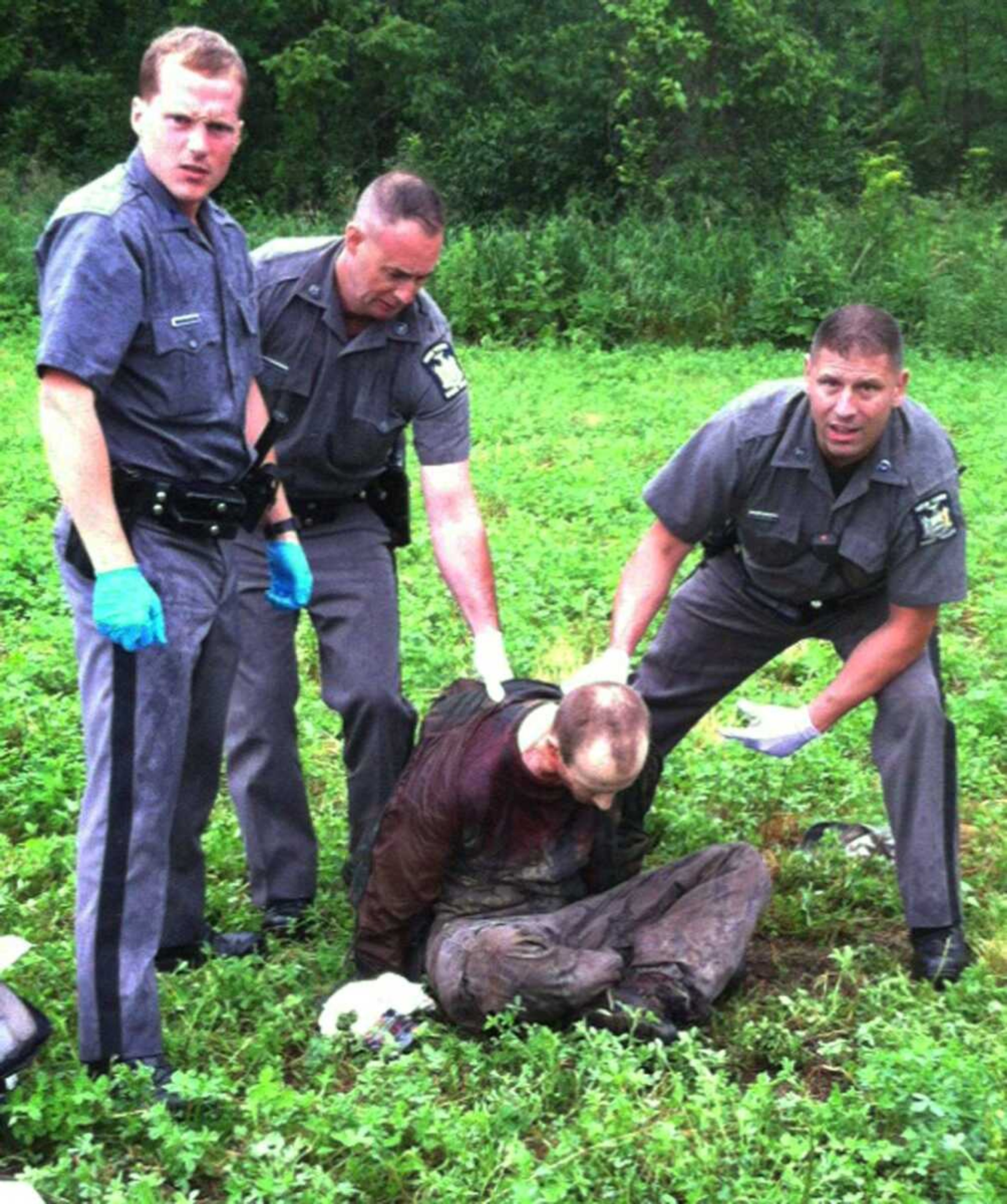 Police stand over David Sweat after he was shot and captured near the Canadian border Sunday in Constable, New York. (Associated Press)