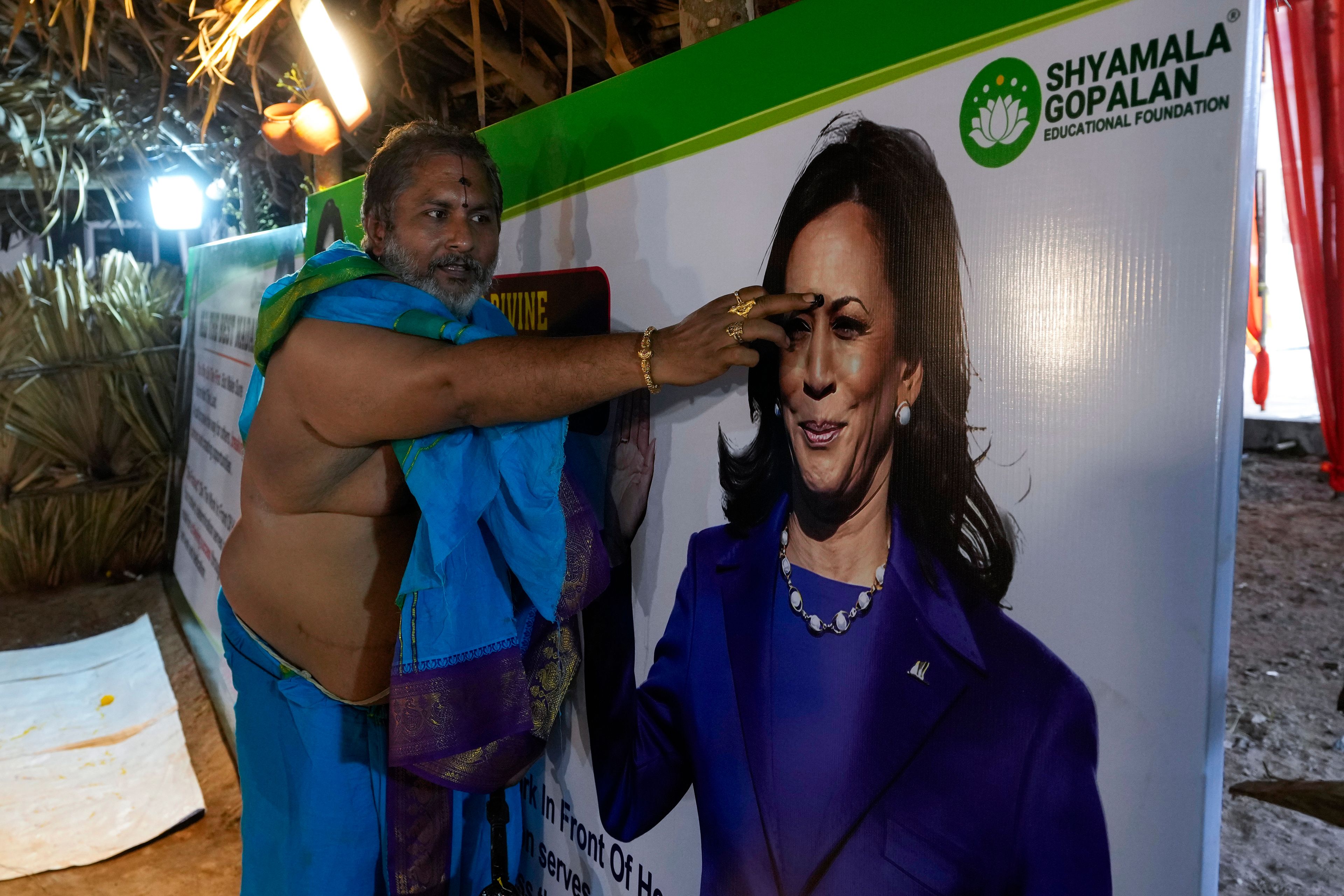 A Hindu priest puts a 'tilak' a forehead mark worn by Hindu women, on a photograph of Democratic presidential nominee Vice President Kamala Harris during special prayers for her victory in the U.S. elections at Palvancha, Telangana, India, Monday, Nov. 4, 2024. The prayers were organized by an educational foundation named after Harris' late mother Shyamala Gopalan. (AP Photo/Mahesh Kumar A.)