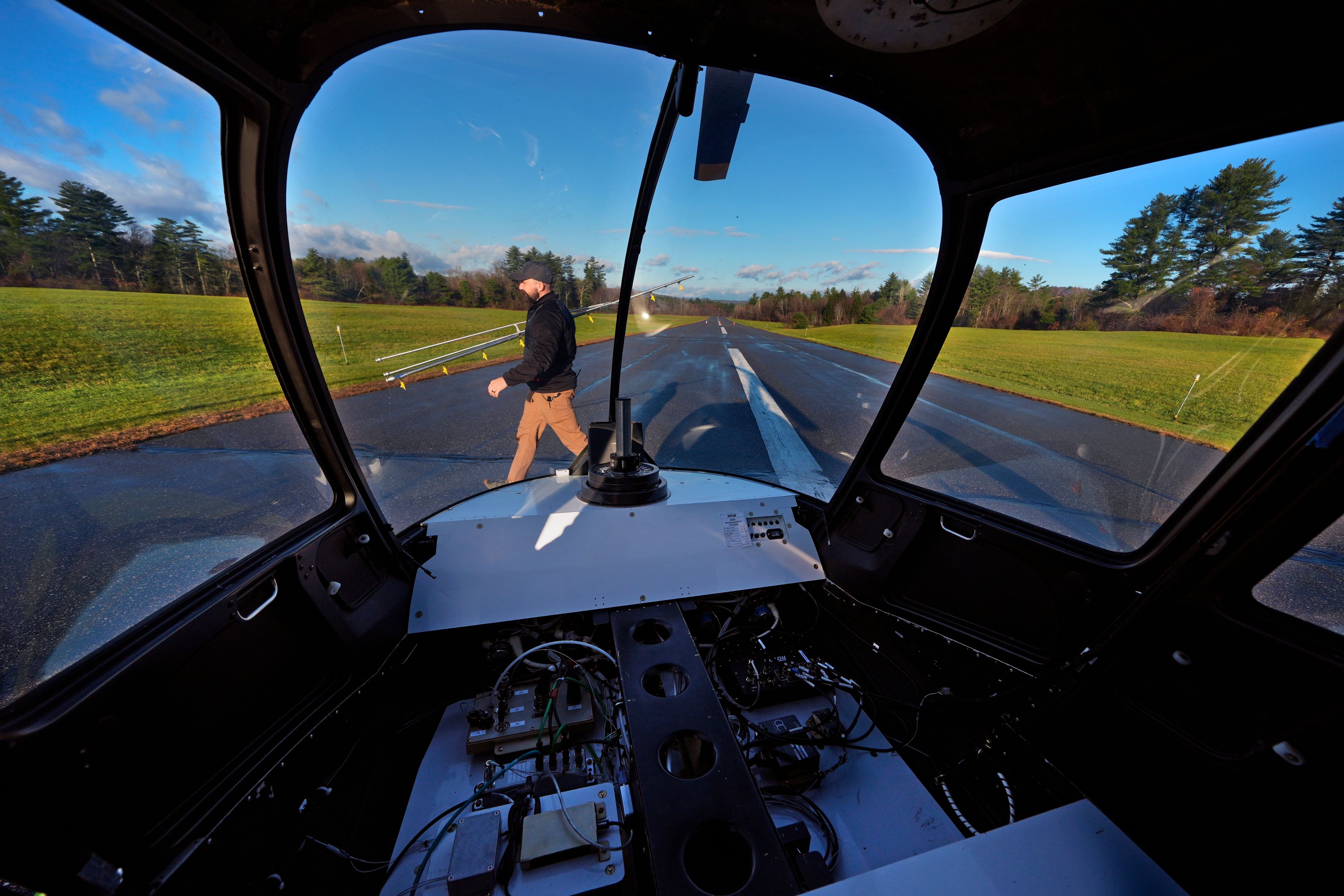 With communications and control components installed where a pilot would sit, Brett Worden, production manager at Rotor Technologies, carries a spray boom following a test flight of an unmanned semi-autonomous helicopter at Intervale Airport, Monday, Nov. 11, 2024, in Henniker, N.H. (AP Photo/Charles Krupa)