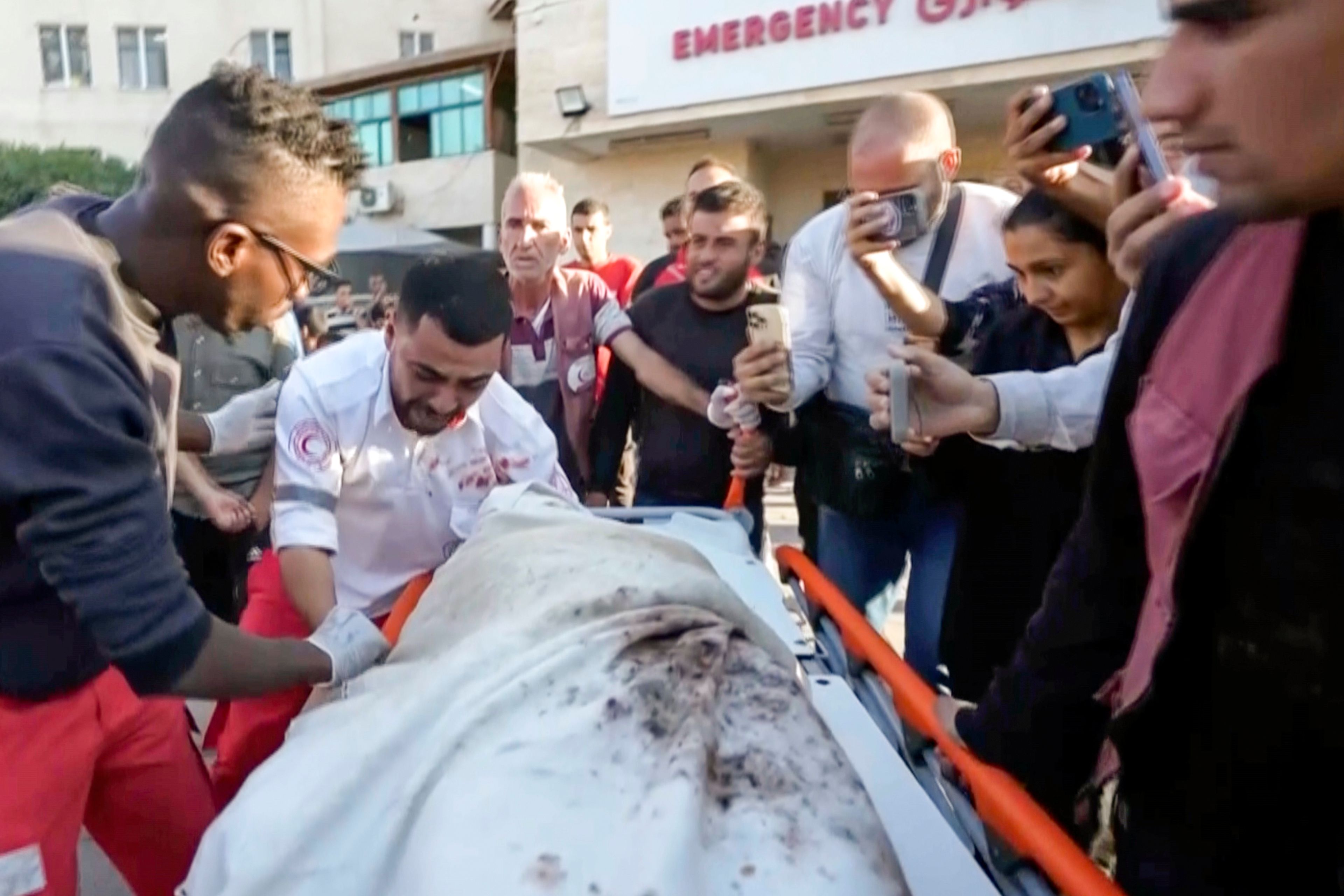 In this image made from an Associated Press video, medic Abed Al Aziz Bardini cries over the body of his mother after he realizes it's her, shouting in Arabic, "Oh god, I swear she is my mother. I didn't know it was her," on Wednesday, Oct. 30, 2024, in Deir al-Balah on the Gaza Strip. (AP Photo/Abed Al Kareem Hana)