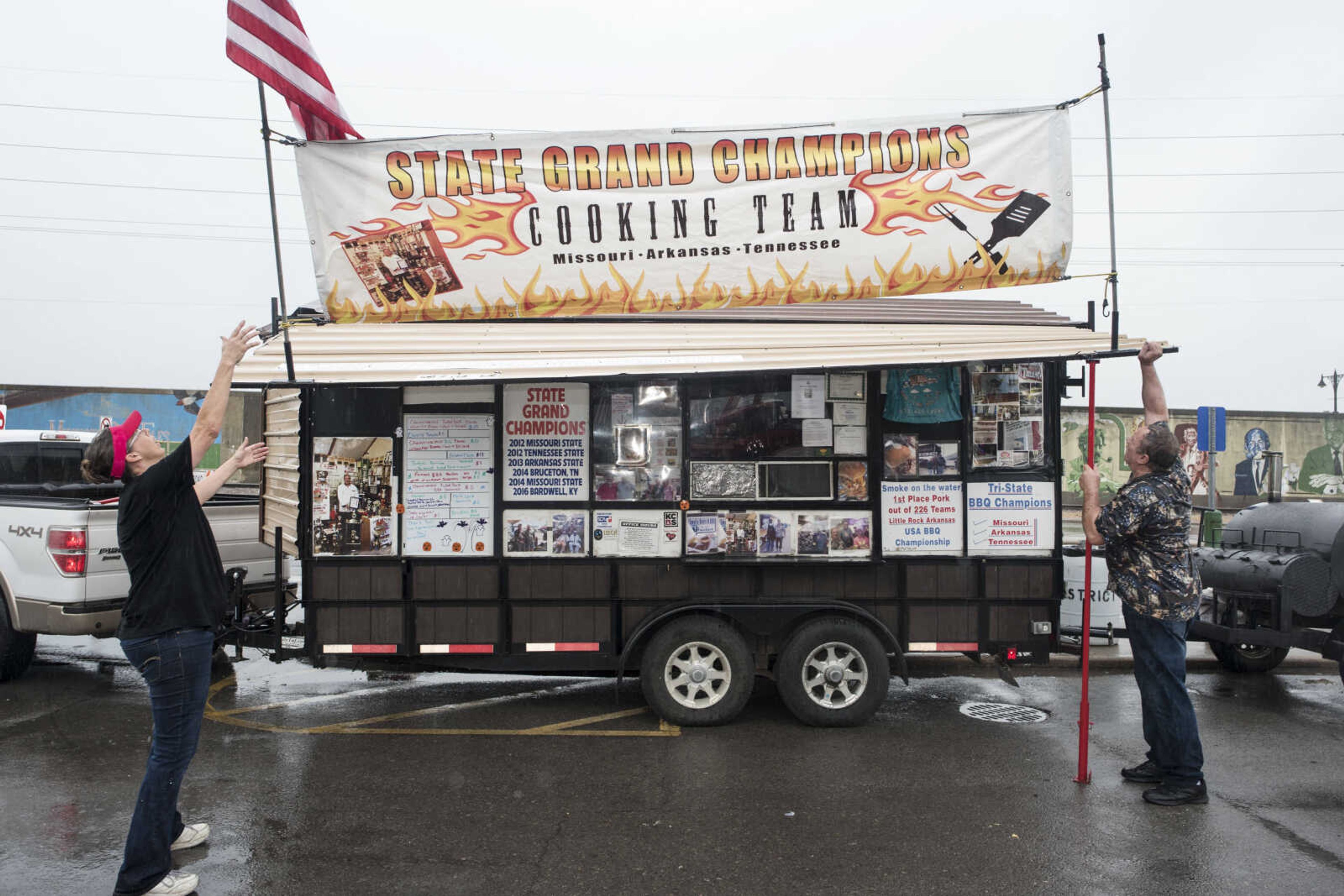 Tim and Kathy Sills lower the canopy on their barbecue trailer after being forced to close early Sunday, Oct. 6, 2019, at the Cape Girardeau Downtown Tailgate Flea Market.