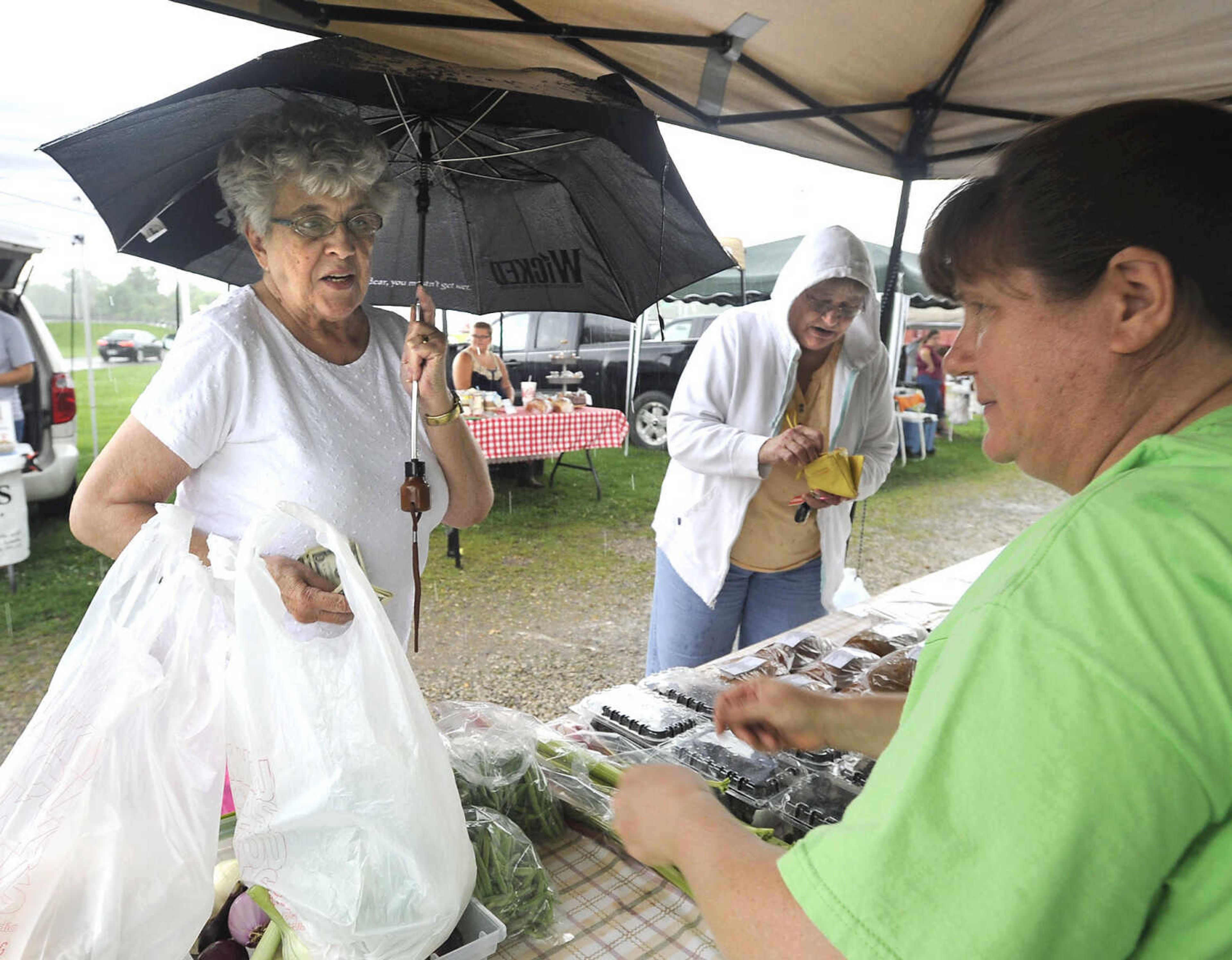 FRED LYNCH ~ flynch@semissourian.com
Lois Seabaugh, left, and Betty Waller, both of Jackson, shop at a vegetable stand operated by Laura Miesner of Frohna, Missouri as rain falls Tuesday, July 7, 2015 at the Jackson Farmer's Market in Jackson.