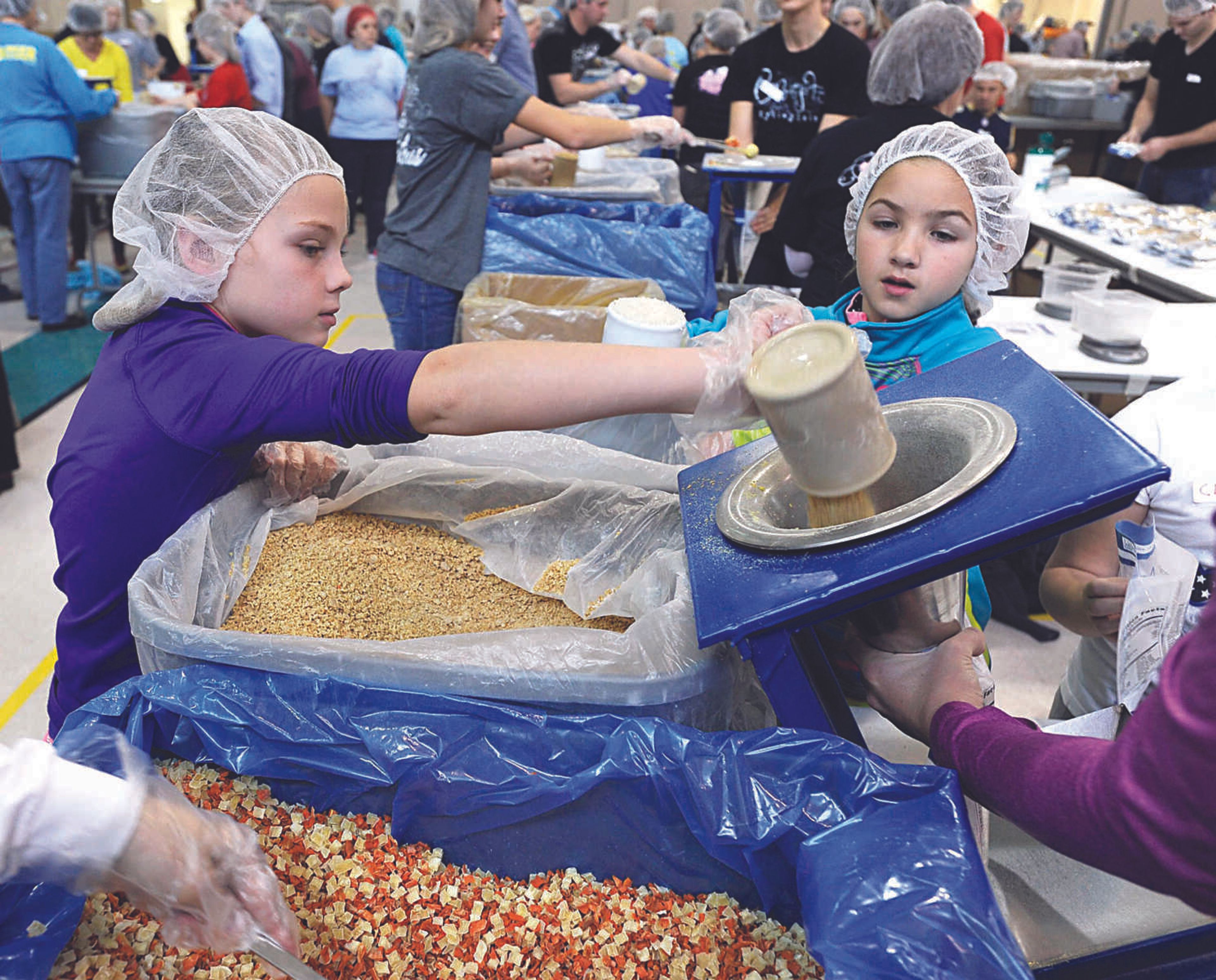 By line:Emerson Pitts, left, pours soy as Ella Clifton waits to add rice on the MannaPack line at the Feed My Starving Children MobilePack event Dec. 7, 2014, at the Osage Centre in Cape Girardeau. More than 3,100 volunteers were expected to fill 800,000 bags with food over the three-day event hosted by LaCroix Church. (Fred Lynch)