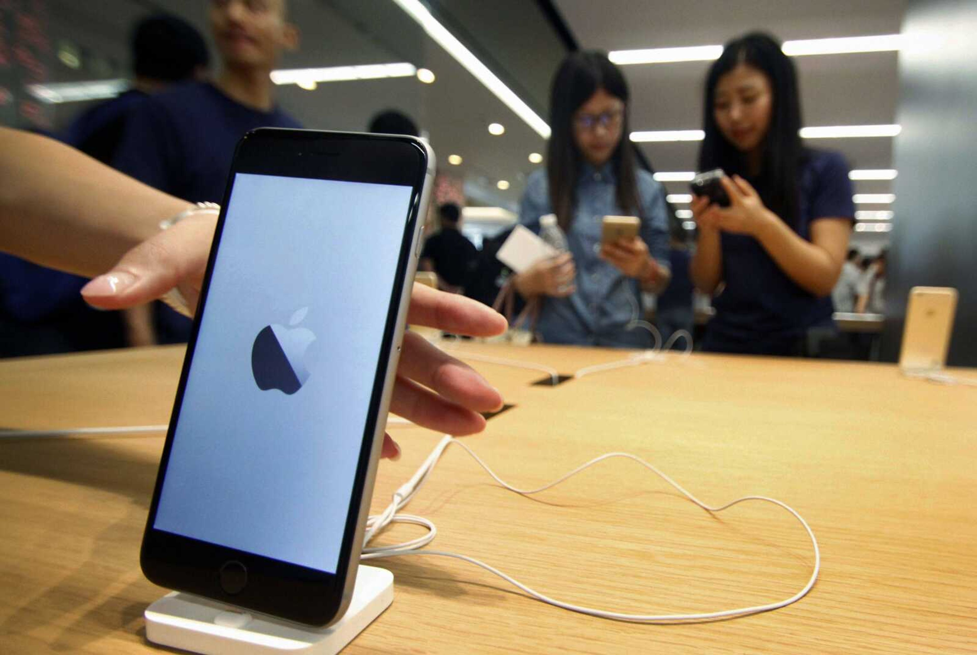 Women try iPhone sets Saturday at a newly opened Apple Store in Nanjing, China. Apple has removed some applications from its App Store after developers in China were tricked into using software tools that added malicious code in an unusual security breach. (Chinatopix via AP)