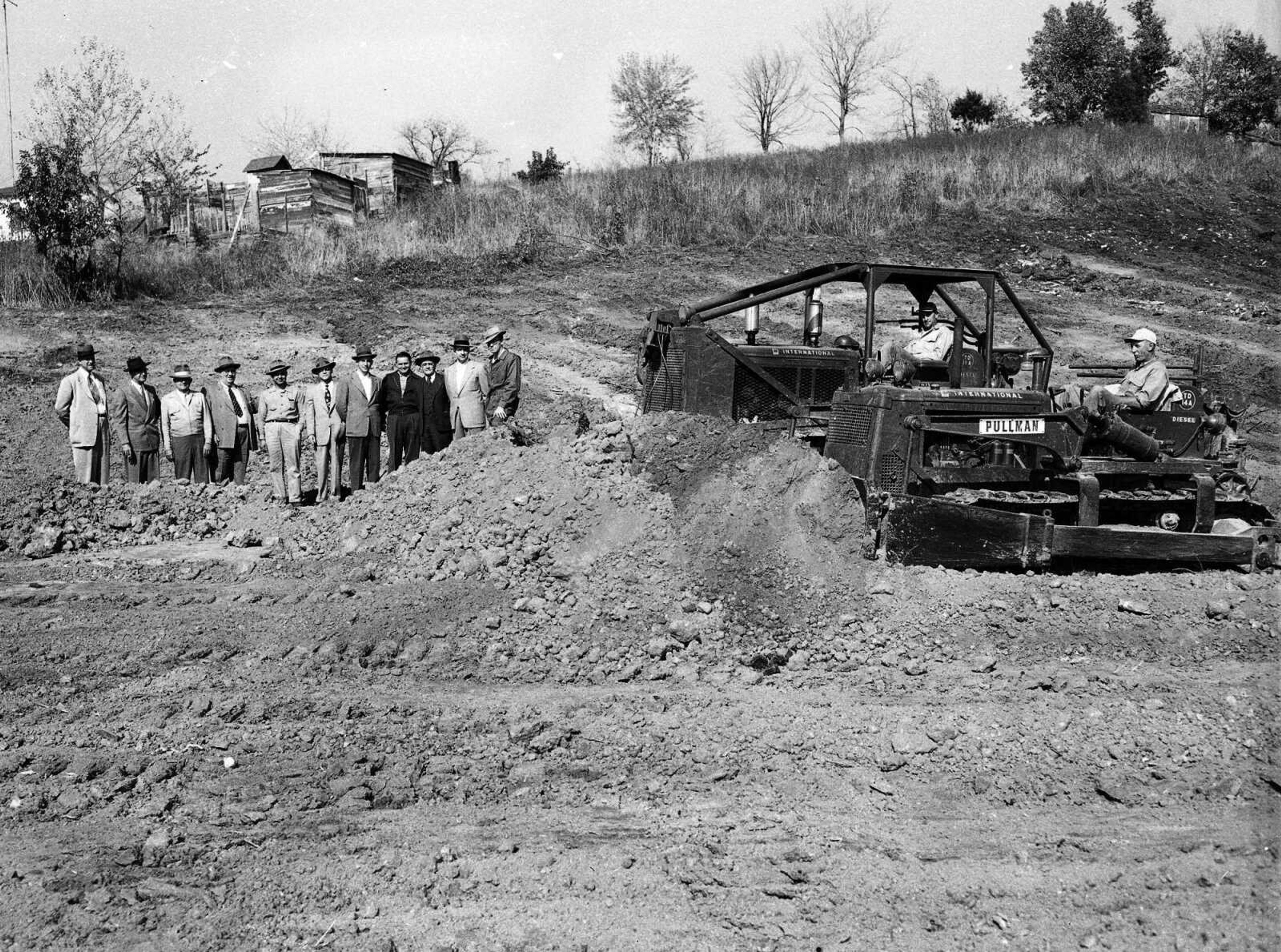 A line of men watch as two huge machines move earth at an unidentified building project. If you can provide information about this image, send librarian Sharon Sanders a note at ssanders@semissourian.com.