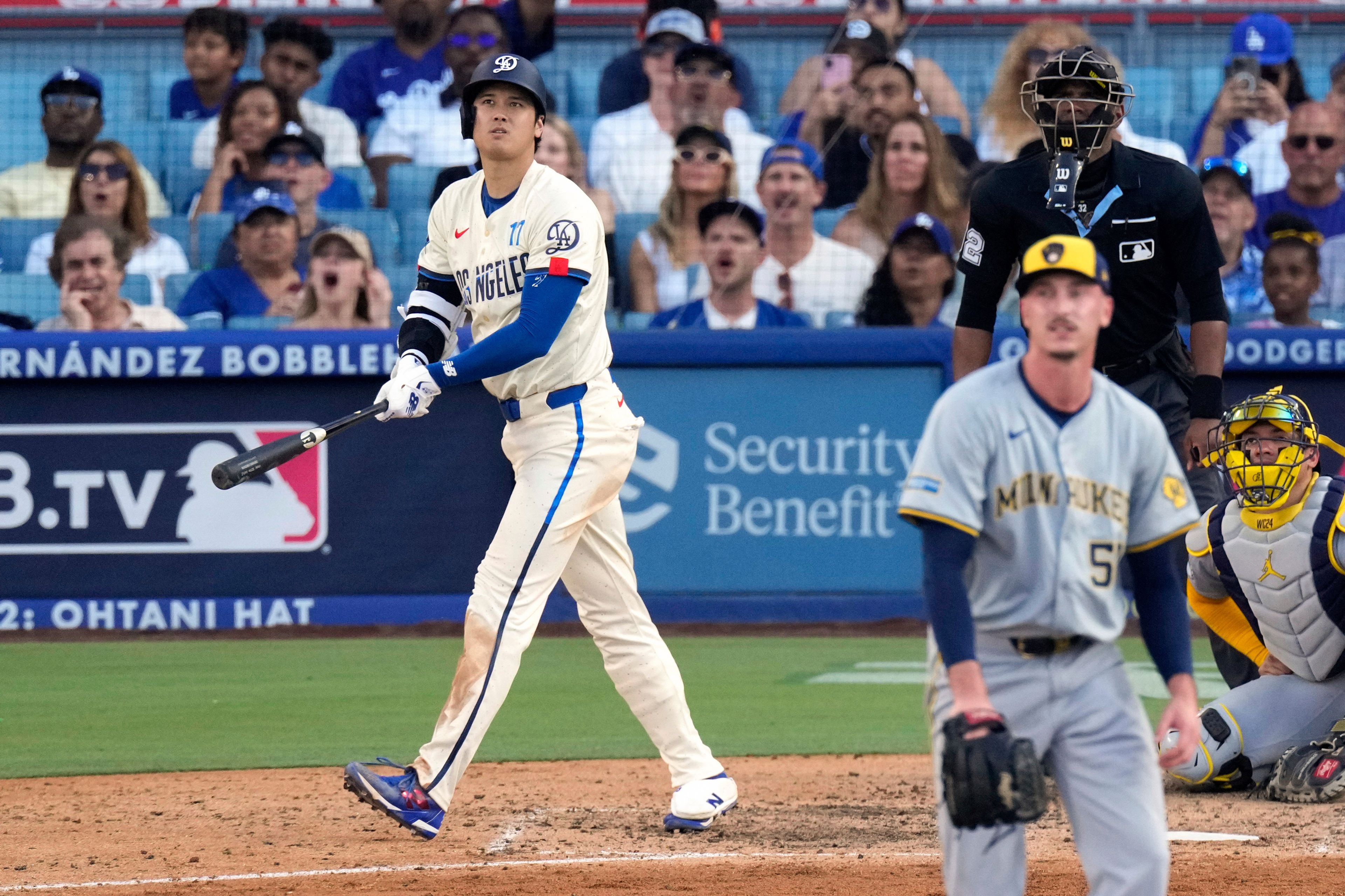 Los Angeles Dodgers' Shohei Ohtani, left, heads to first for a solo home run as Milwaukee Brewers relief pitcher Bryan Hudson, second from left, and catcher William Contreras, right, watch along with home plate umpire Edwin Moscoso during the eighth inning of a baseball game Saturday, July 6, 2024, in Los Angeles. (AP Photo/Mark J. Terrill)