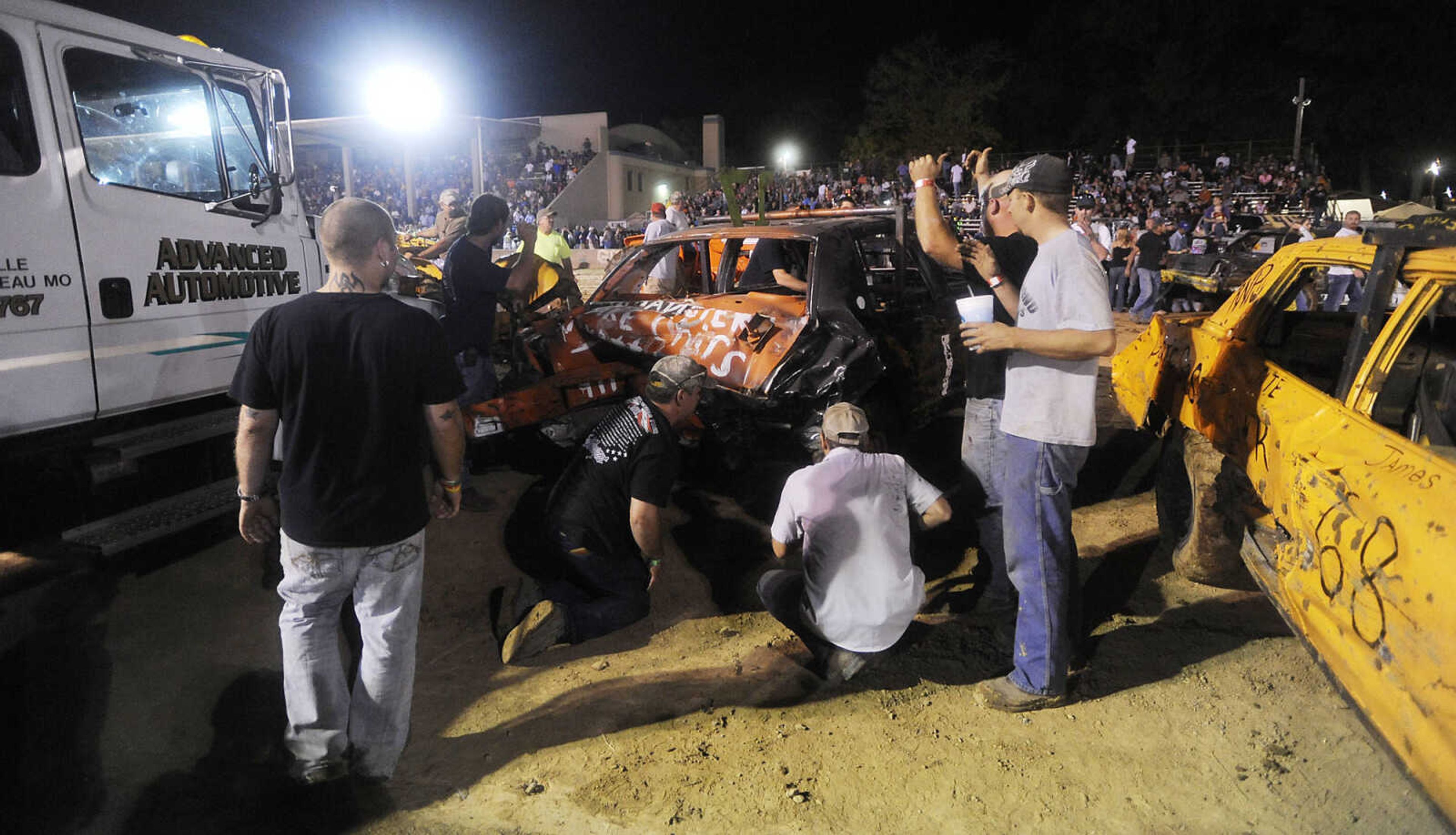 Crew members asses the damage done to Mark Mayfield's car during the Dual Demo Derby at the SEMO District Fair Tuesday, September 11, at Arena Park in Cape Girardeau. Just seconds into thier heat Mayfield's car was disabled and teammate Leslie Welker was injured.