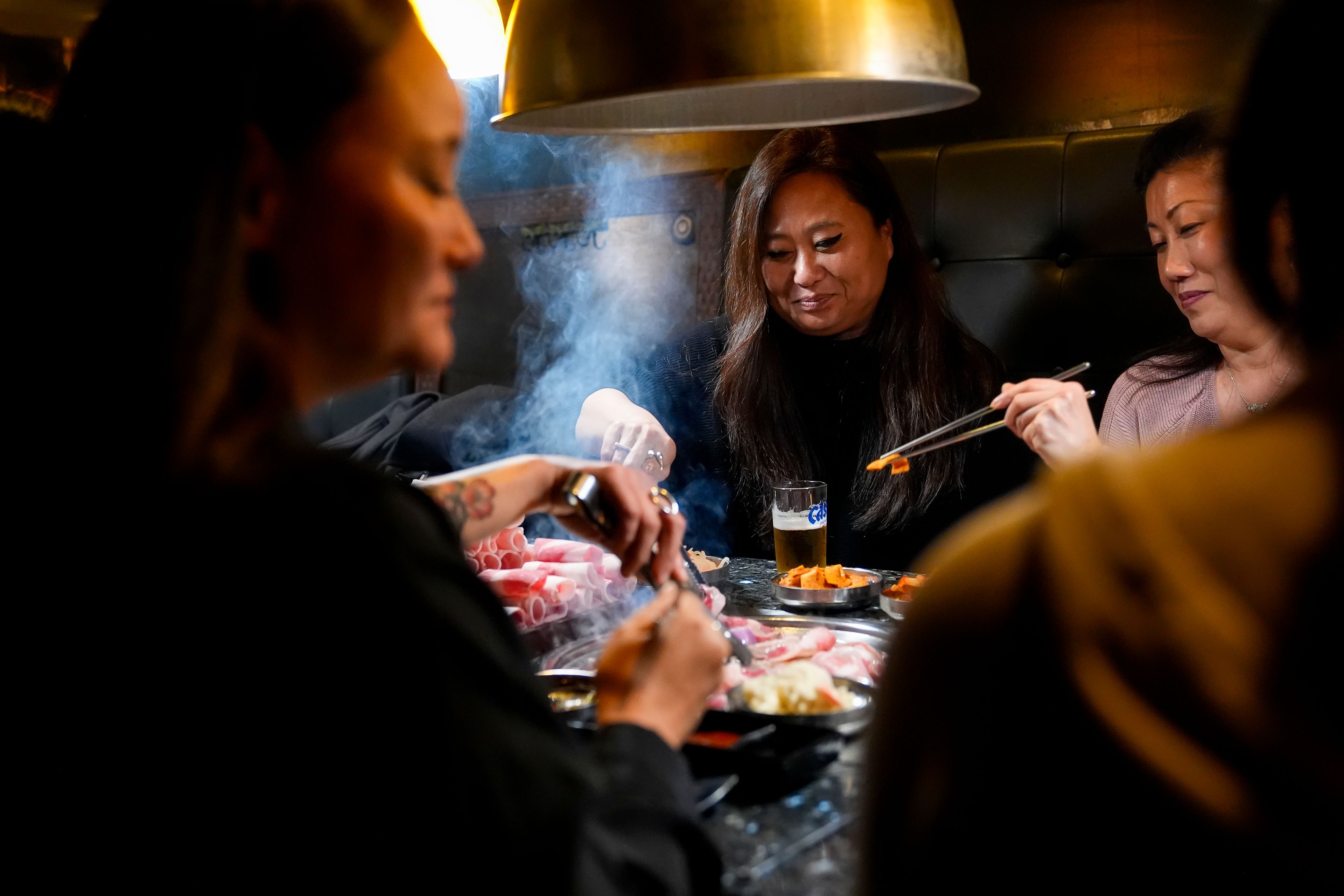 Rebecca Kimmel, center, eats with fellow Korean adoptees, Jenny Kelly, left, and Michelle Leco, right, at Yetgol Old Village Korean BBQ Sunday, Jan. 28, 2024, in Seattle. Kimmel still does not know, and may never know, who she is. All she knows is who she's not. (AP Photo/Lindsey Wasson)