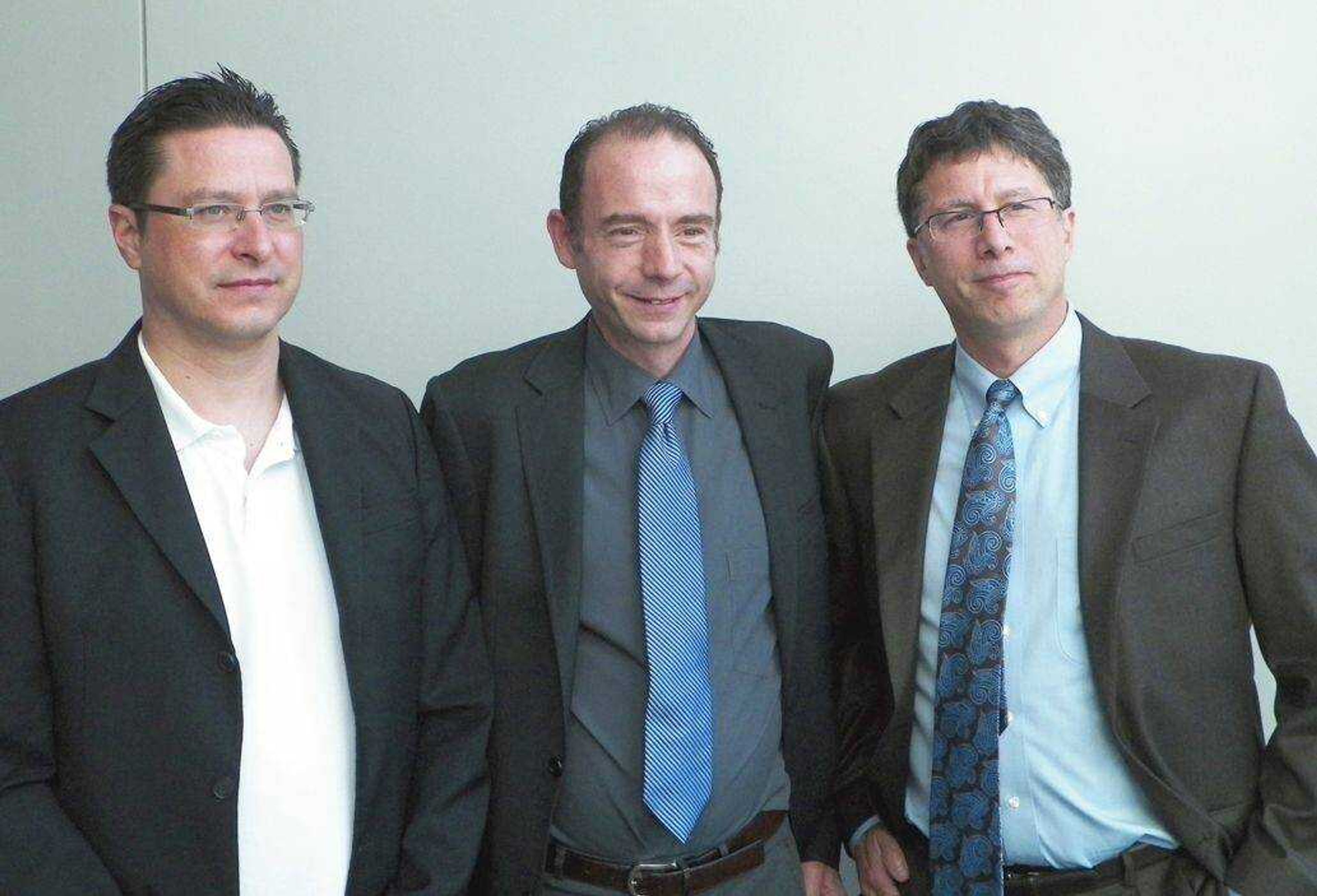 Dr. Gero Hutter of Germany, left, Timothy Ray Brown, center, and Dr. David Curiel of Washington University pose for a picture after Hutter discussed his treatment of Brown at a symposium on gene therapy cures Wednesday at Washington University in St. Louis. (Jim Salter ~ Associated Press)