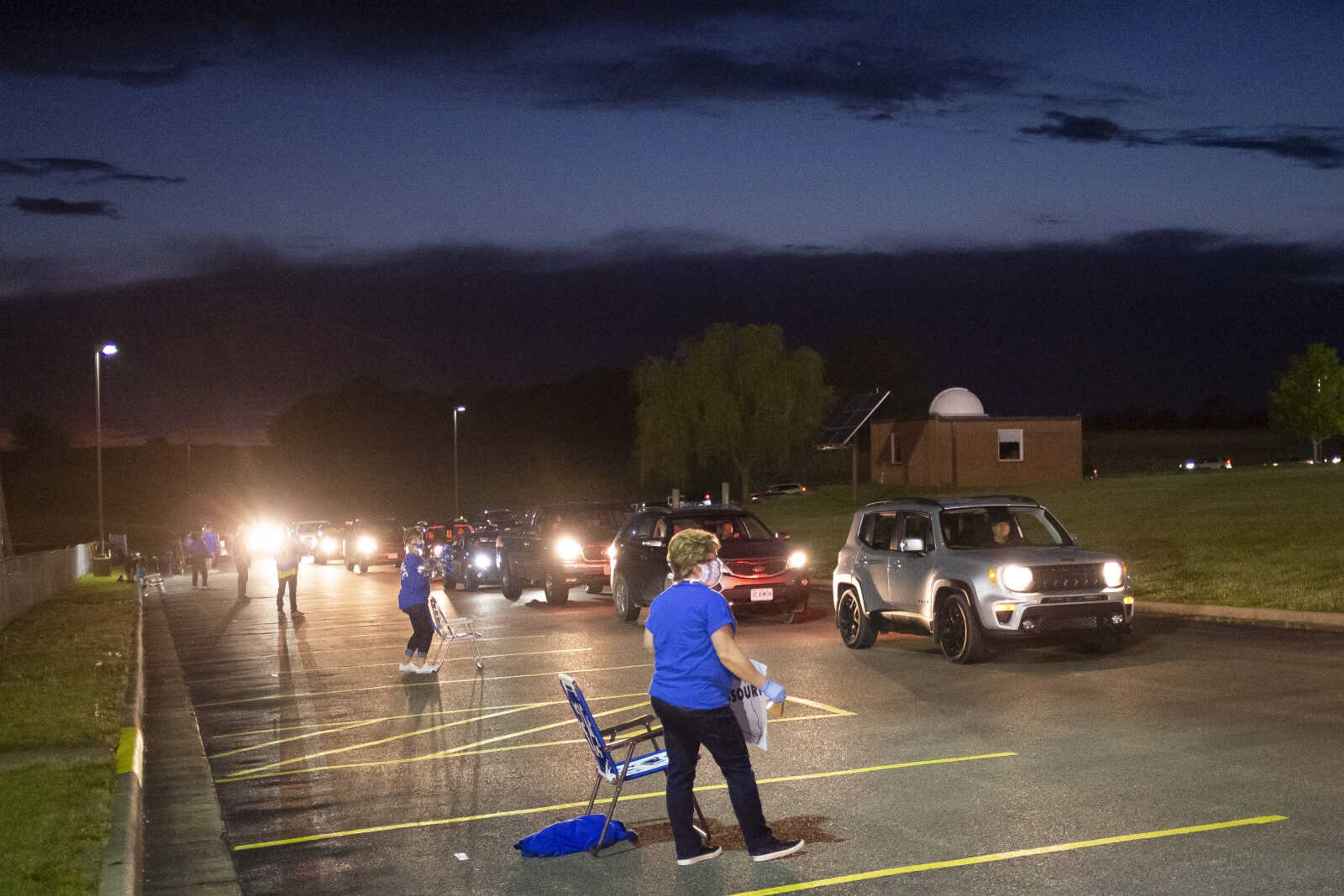 Vehicles make their way around the campus of Notre Dame Regional High School near Kim St. Cin, guidance office manager at the school, during a "Friday night lights" senior drive-through event Friday, May 1, 2020, at the Cape Girardeau school.