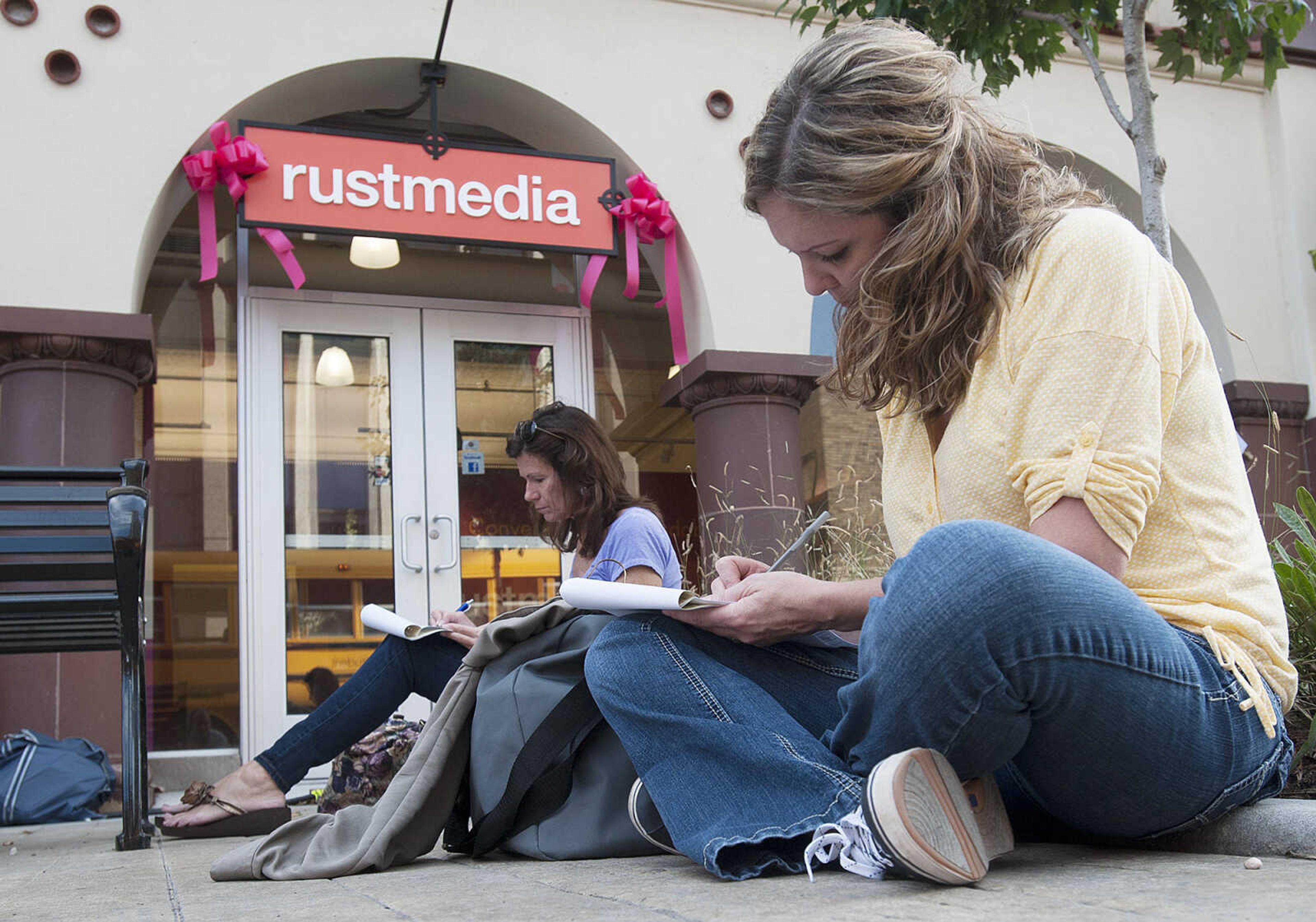 ADAM VOGLER ~ avogler@semissourian.com
Nikki Caldwell, right, and Cheryl Hill, both of Cape Girardeau, sit on the sidewalk while they fill out paperwork before working as extras on the 20th Century Fox feature film "Gone Girl," Thursday, Oct. 3, in downtown Cape Girardeau.