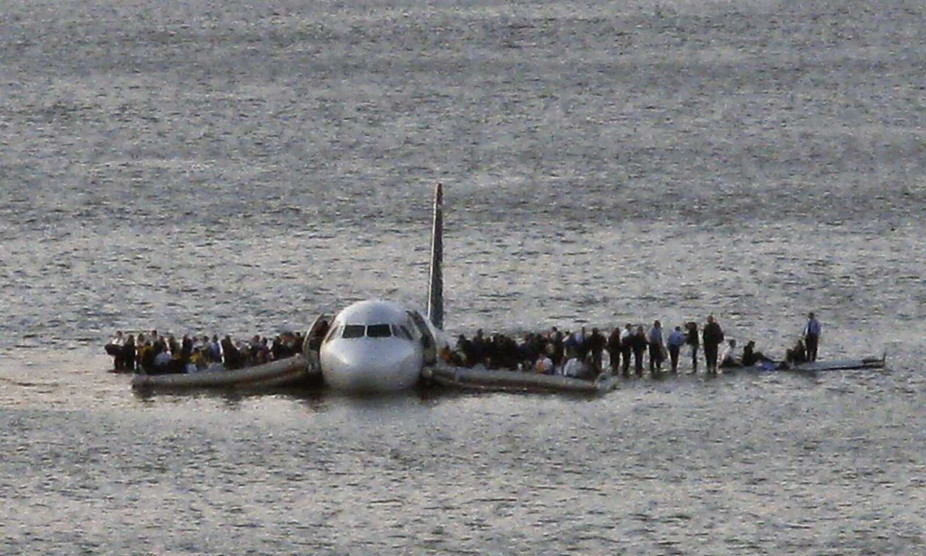 Airline passengers wait to board a ferry to be rescued on the wings of a US Airways Airbus 320 jetliner that safely ditched in the frigid waters of the Hudson River in New York, Thursday Jan. 15, 2009 after a flock of birds knocked out both its engines. All 155 people on board survived. (AP Photo/Steven Day)