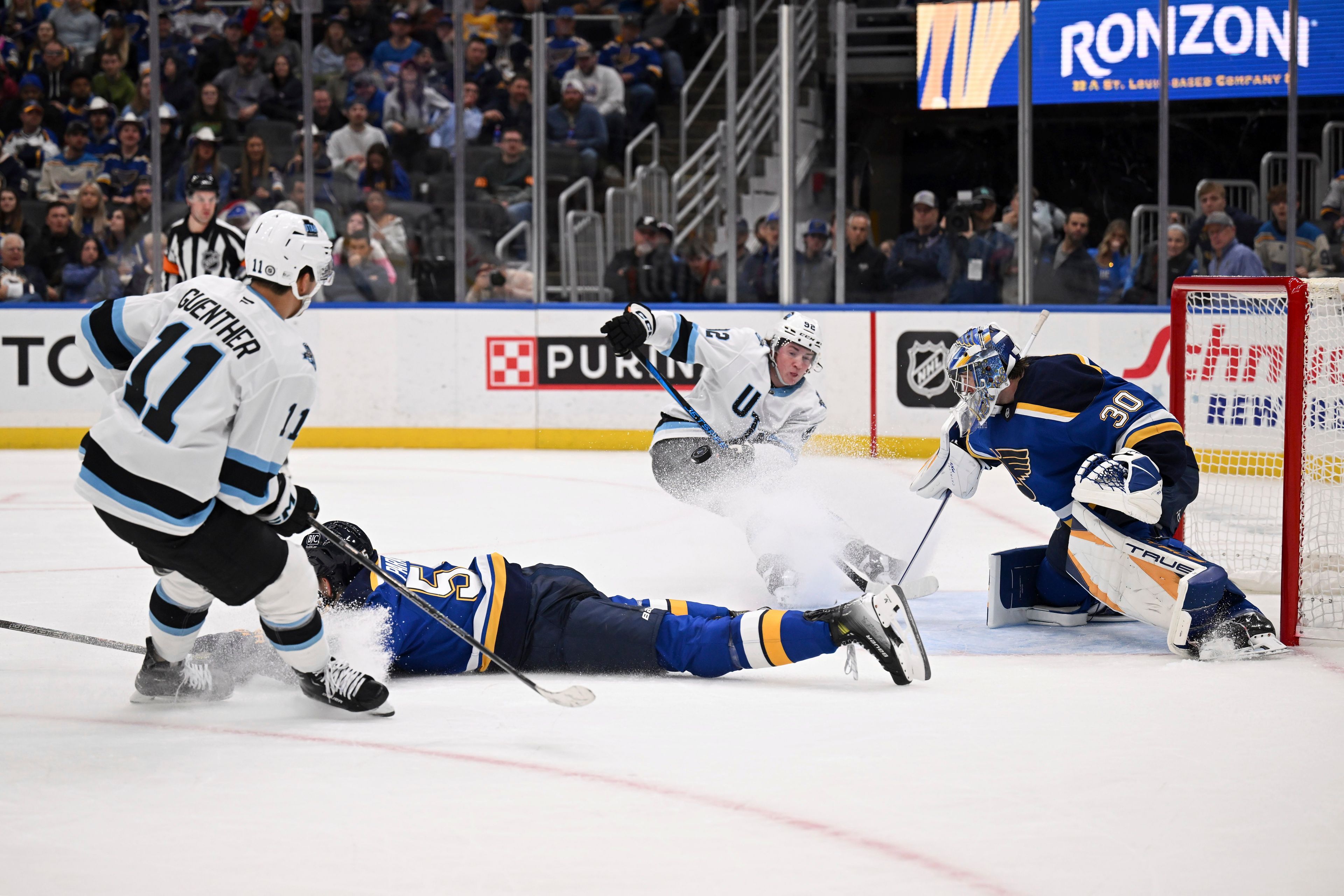 Utah Hockey Club's Dylan Guenther (11) and Utah Hockey Club's Vladislav Kolyachonok (52), back center, watch on as St. Louis Blues' Joel Hofer (30) and St. Louis Blues' Colton Parayko (55) defend the net during the third period of an NHL hockey game Thursday, Nov. 7, 2024, in St. Louis. (AP Photo/Connor Hamilton)