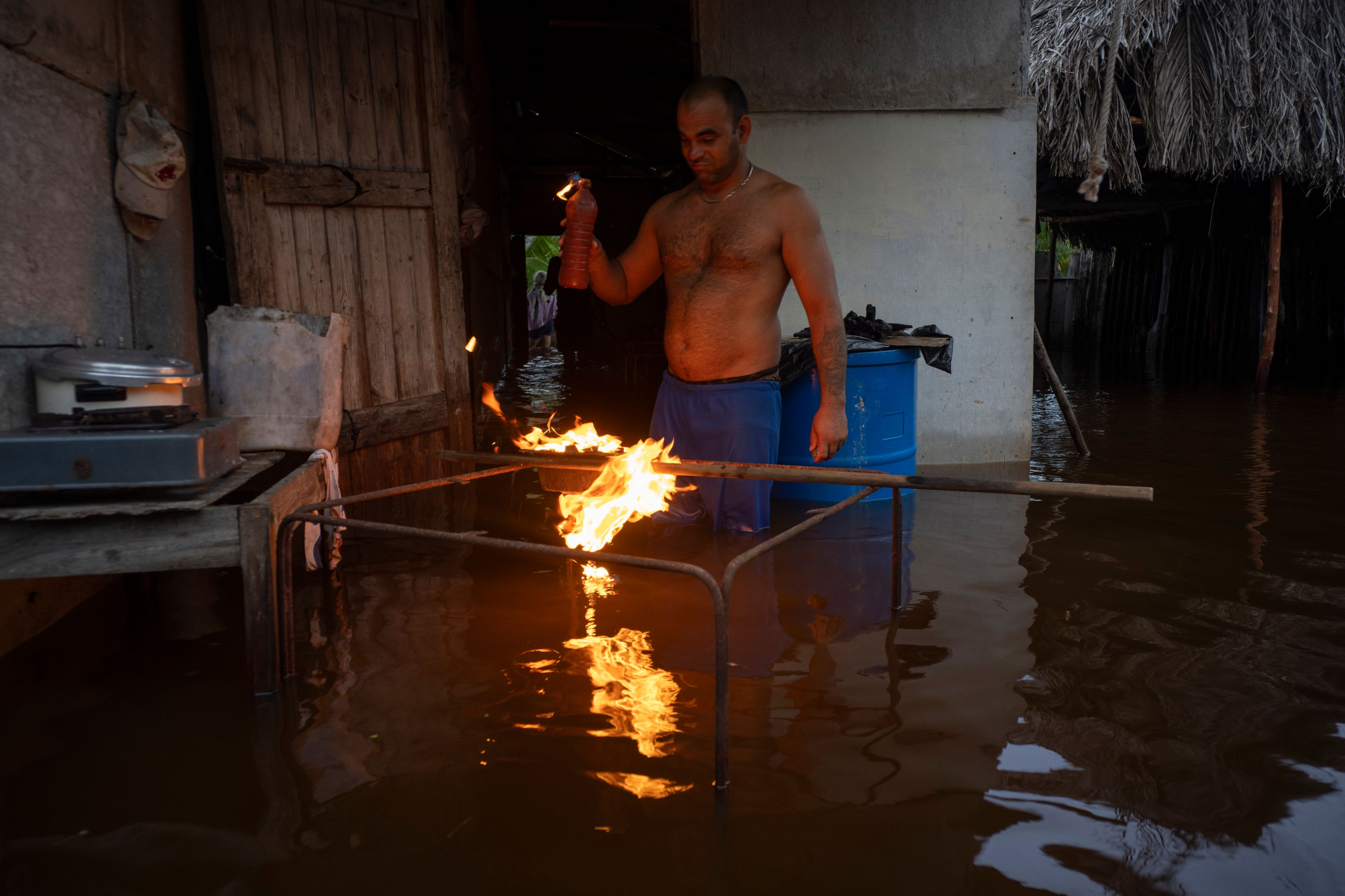 A man lights charcoal to cook dinner in his flooded home after the passage of Hurricane Helene in Guanimar, Artemisa province, Cuba, Sept. 25, 2024. (AP Photo/Ramon Espinosa)