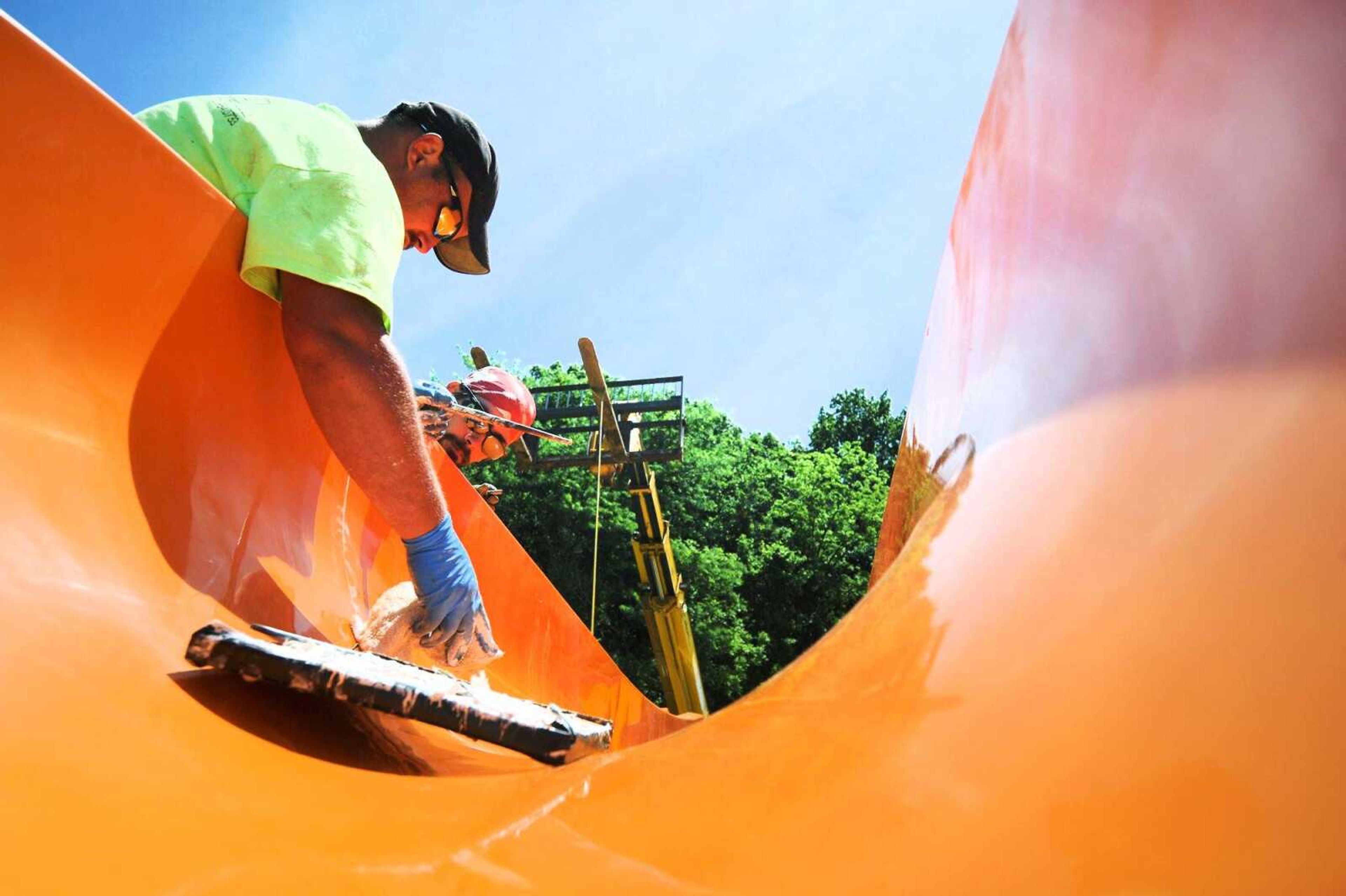 T.J. Amerson, right, watches as Patrick Armstrong applies construction sealant to the top section of the new drop slide Tuesday at Cape Splash in Cape Girardeau. (Laura Simon)