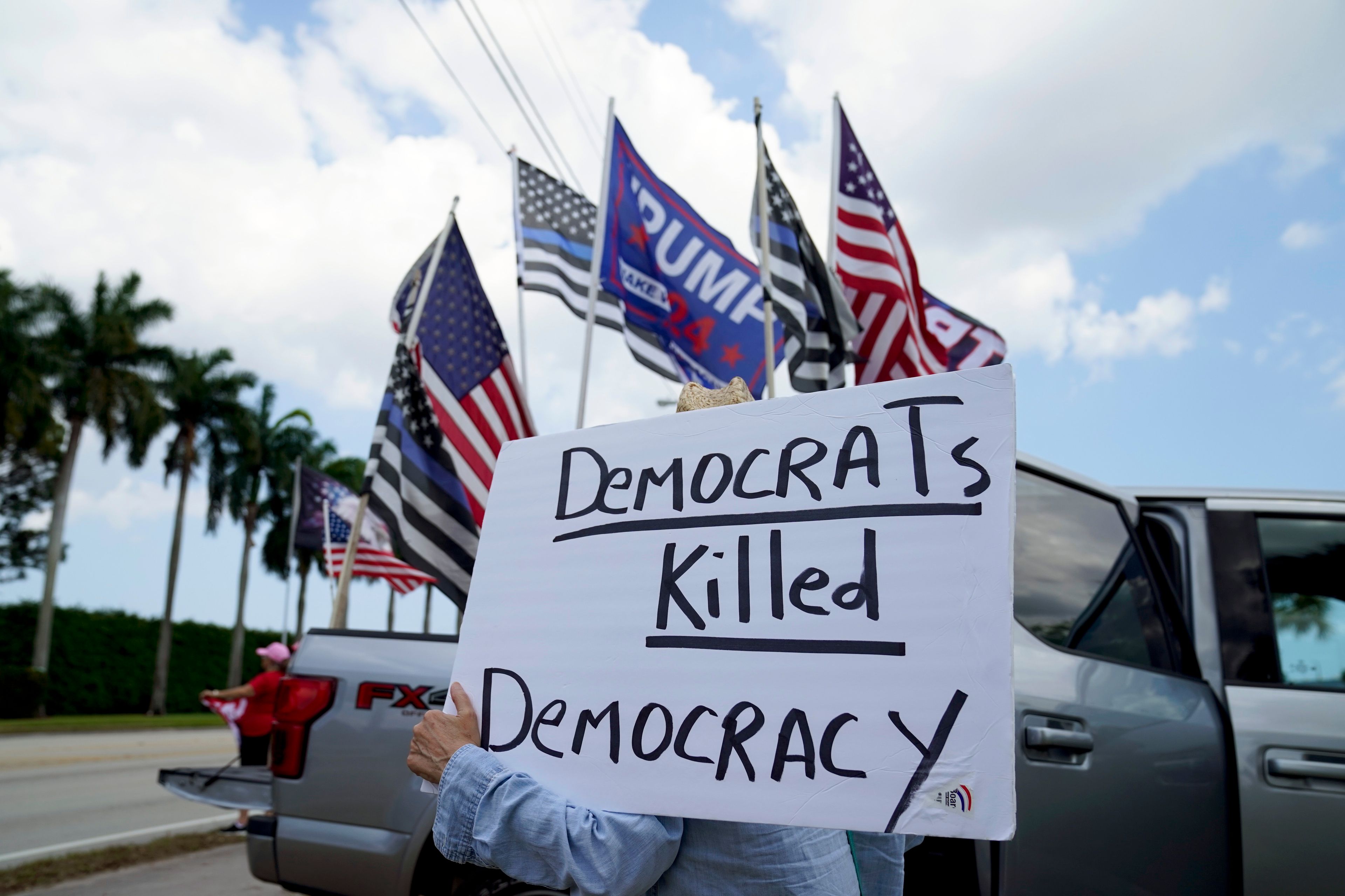 FILE - A supporter of former President Donald Trump holds a sign outside Trump International Golf Club, April 2, 2023, in West Palm Beach, Fla. (AP Photo/Evan Vucci, File)