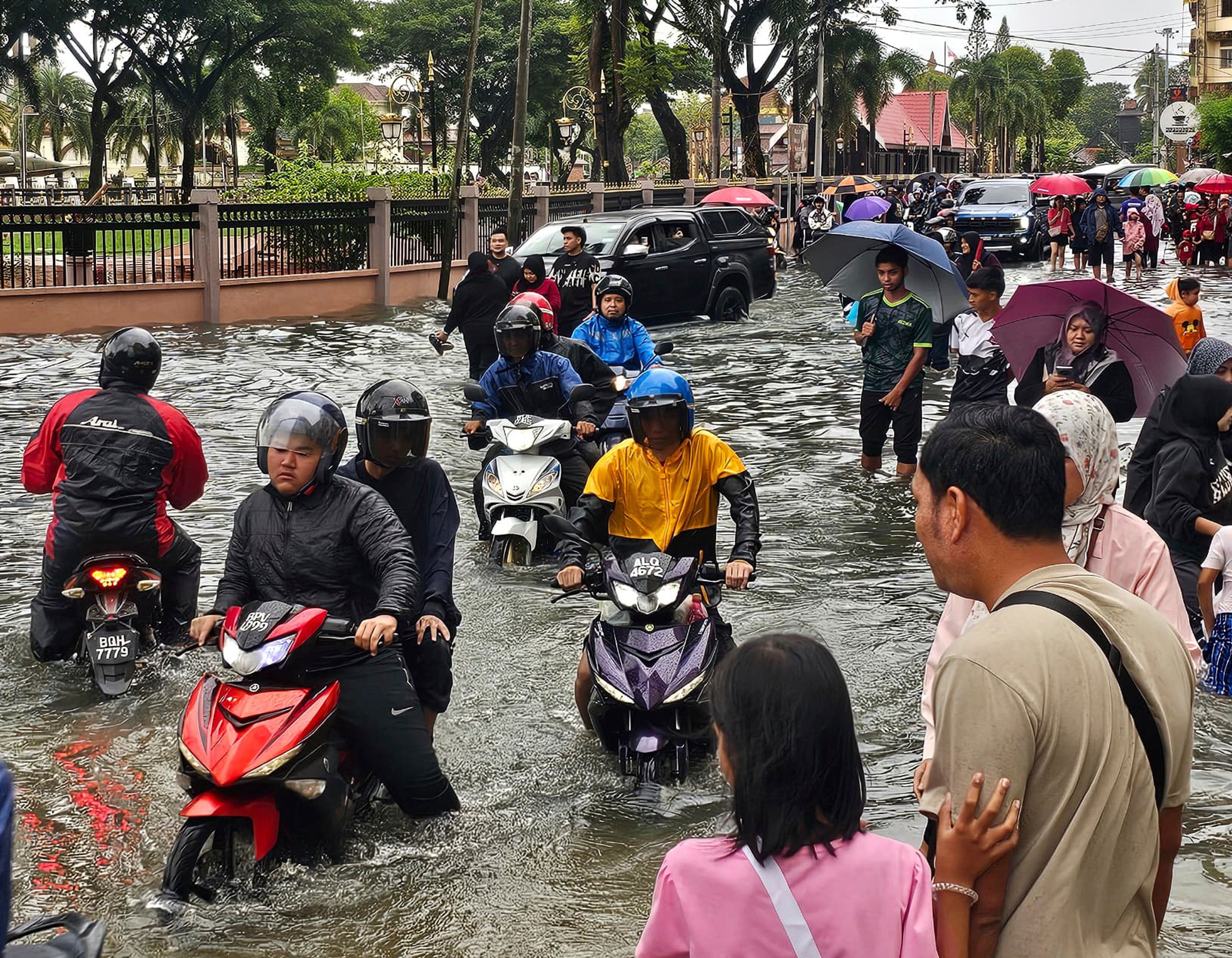 Motorist cross a flooded street after heavy monsoon rains in downtown Kota Bharu, Kelantan, Malaysia, Friday, Nov. 29, 2024. (AP Photo/Loo Kok Chong)