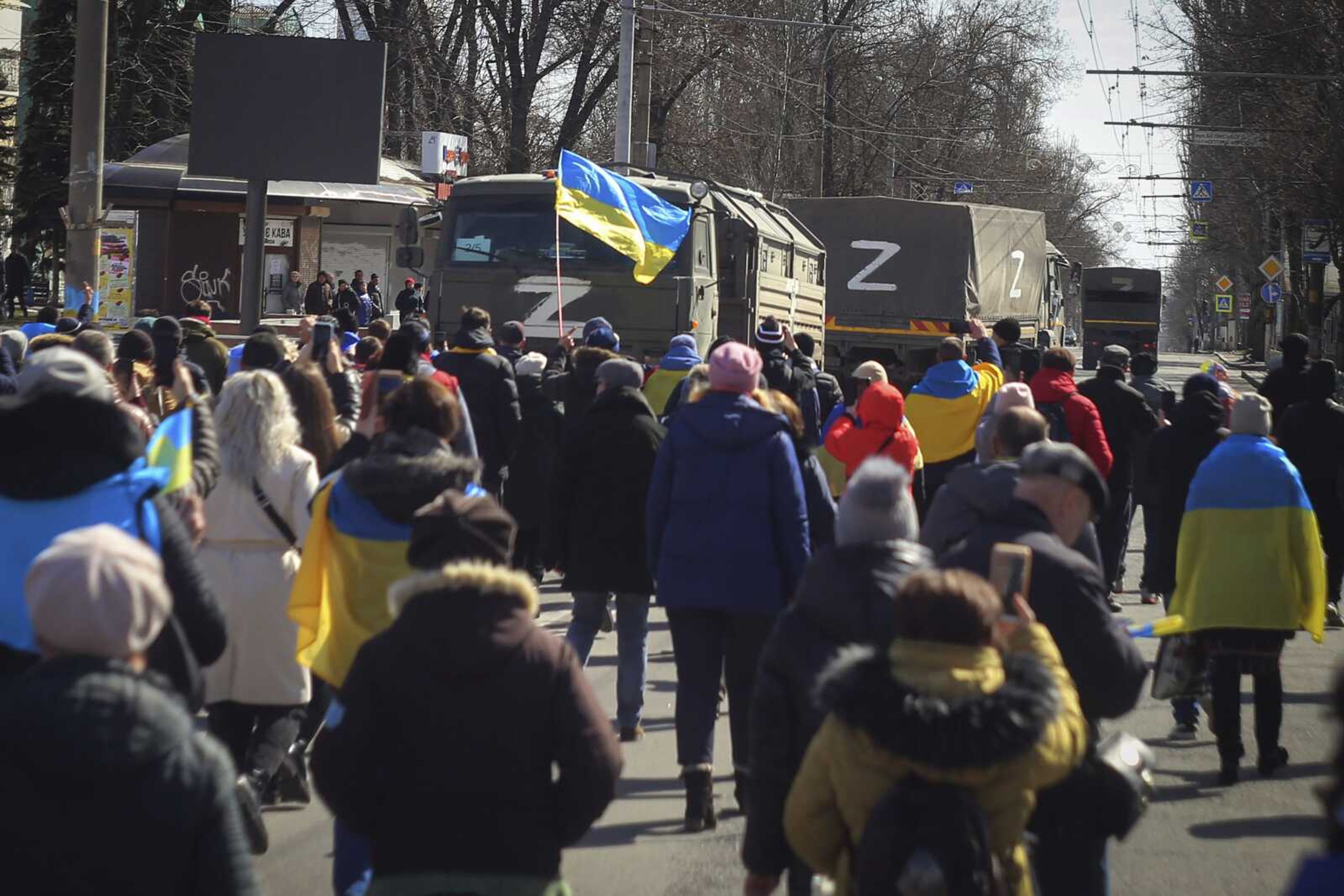 People with Ukrainian flags walk toward Russian army trucks during a rally against the Russian occupation March 20 in Kherson, Ukraine.