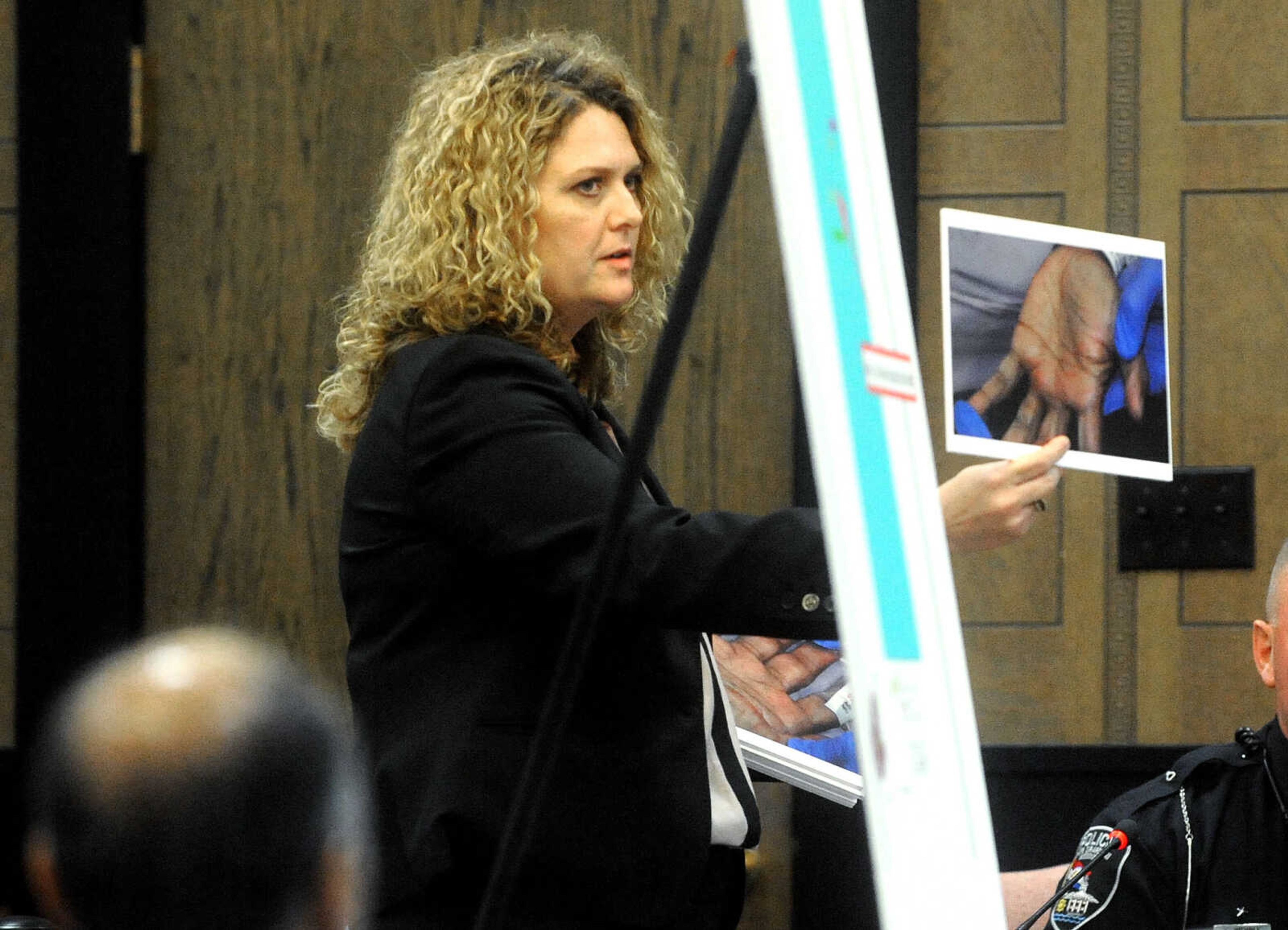 LAURA SIMON ~ lsimon@semissourian.com

Cape Girardeau County Assistant Prosecuting Attorney, Angel Woodruff, holds up a photo of George Joseph's hand, taken by a member of the Cape Girardeau Police Department, Monday, July 20, 2015, during the first day of Joseph's double-murder trial at the Cape Girardeau County Courthouse in Jackson, Missouri. Joseph is accused in the 2013 shooting deaths of his wife, Mary Joseph, and son, Matthew Joseph, at their home on West Cape Rock Drive.