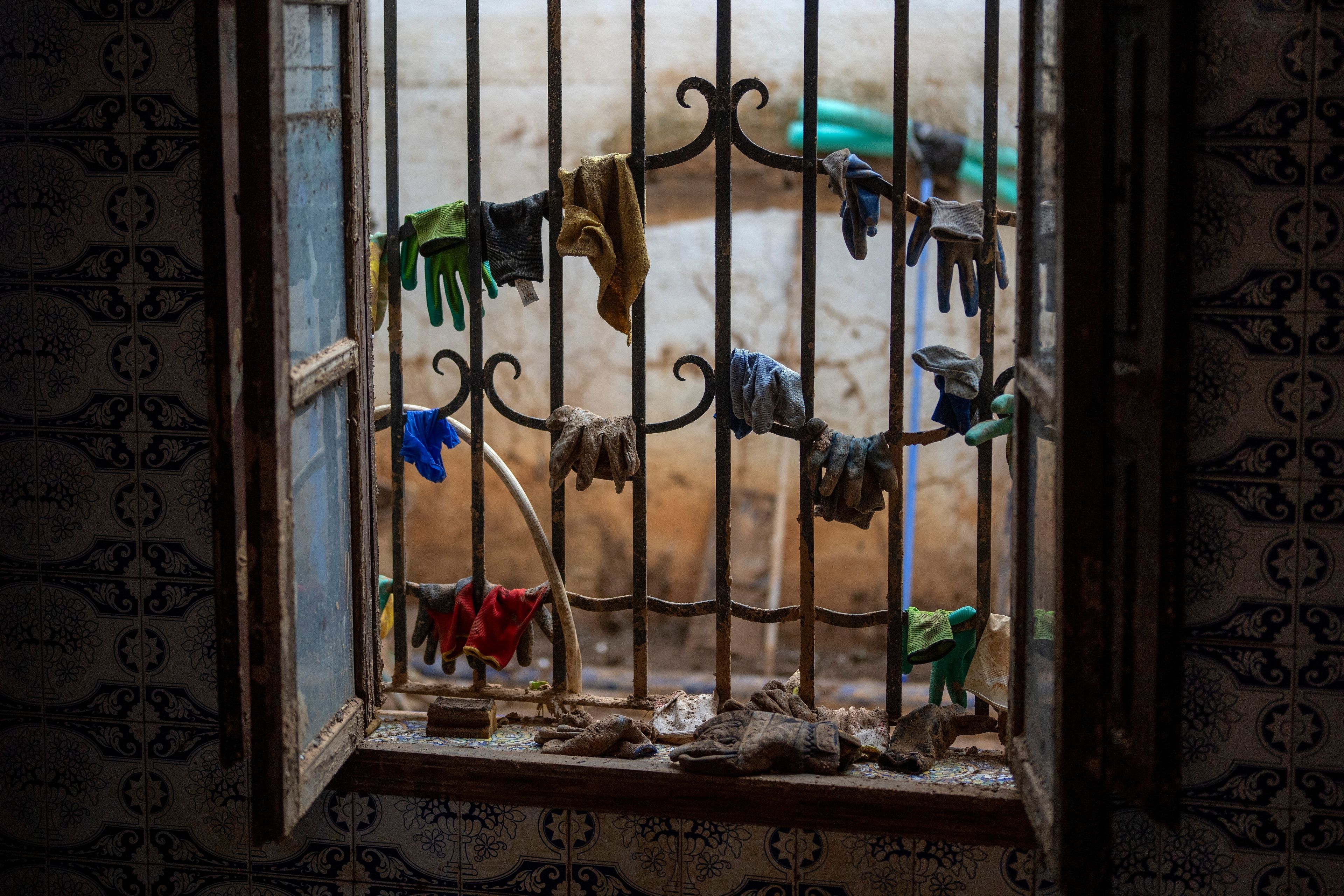 Gloves and cleaning utensils hang in a window during the clean-up after the floods, in a house in Masanasa, Valencia, Spain, Thursday, Nov. 7, 2024. (AP Photo/Emilio Morenatti)