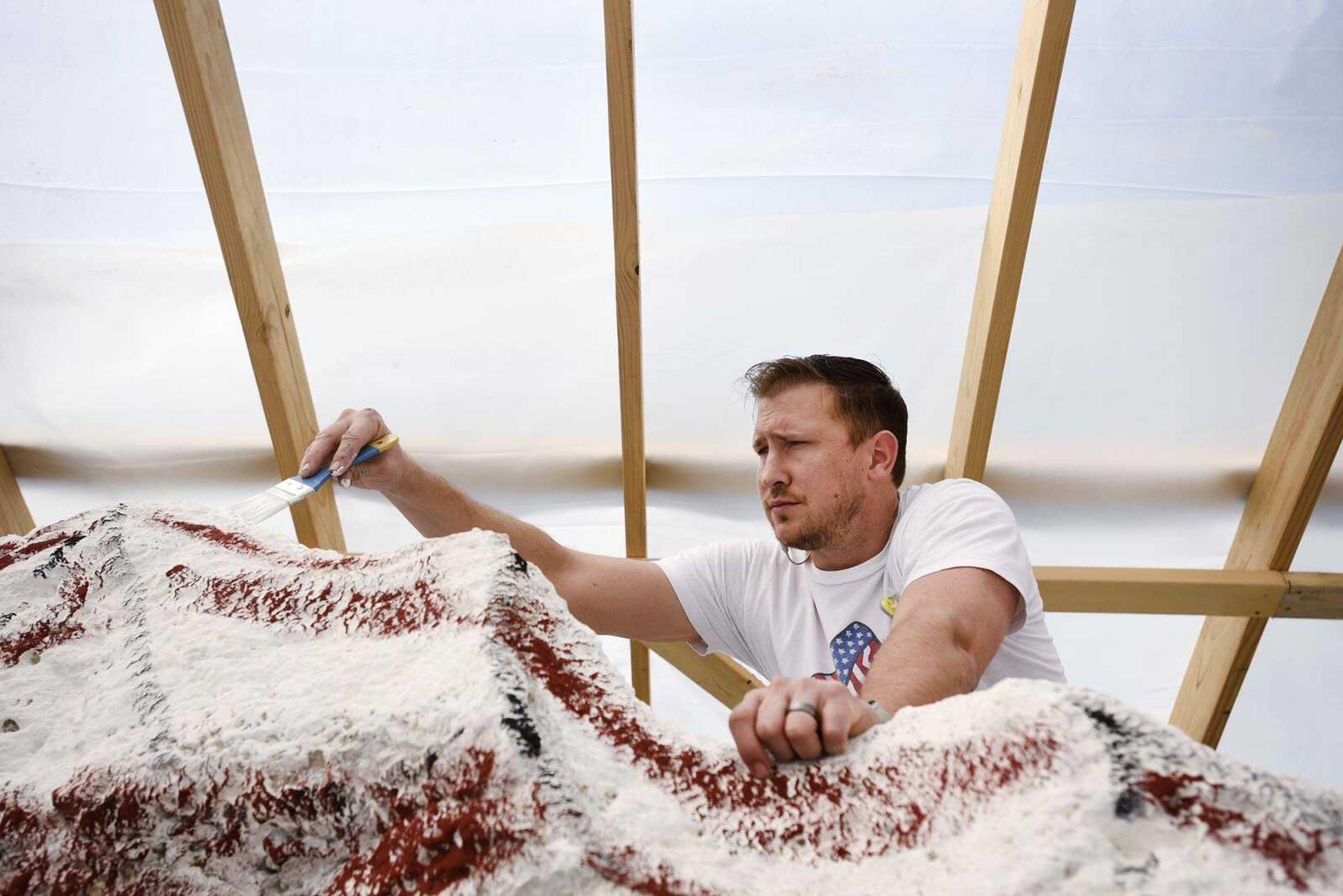 Iowa artist Ray Ã¾Ã„ÃºBubbaÃ¾Ã„Ã¹ Sorensen II, paints a patriotic tableau on 32-ton rock under a temporary shelter on Wednesday at Cape Girardeau County Park North. The rock is part of Veterans Plaza.