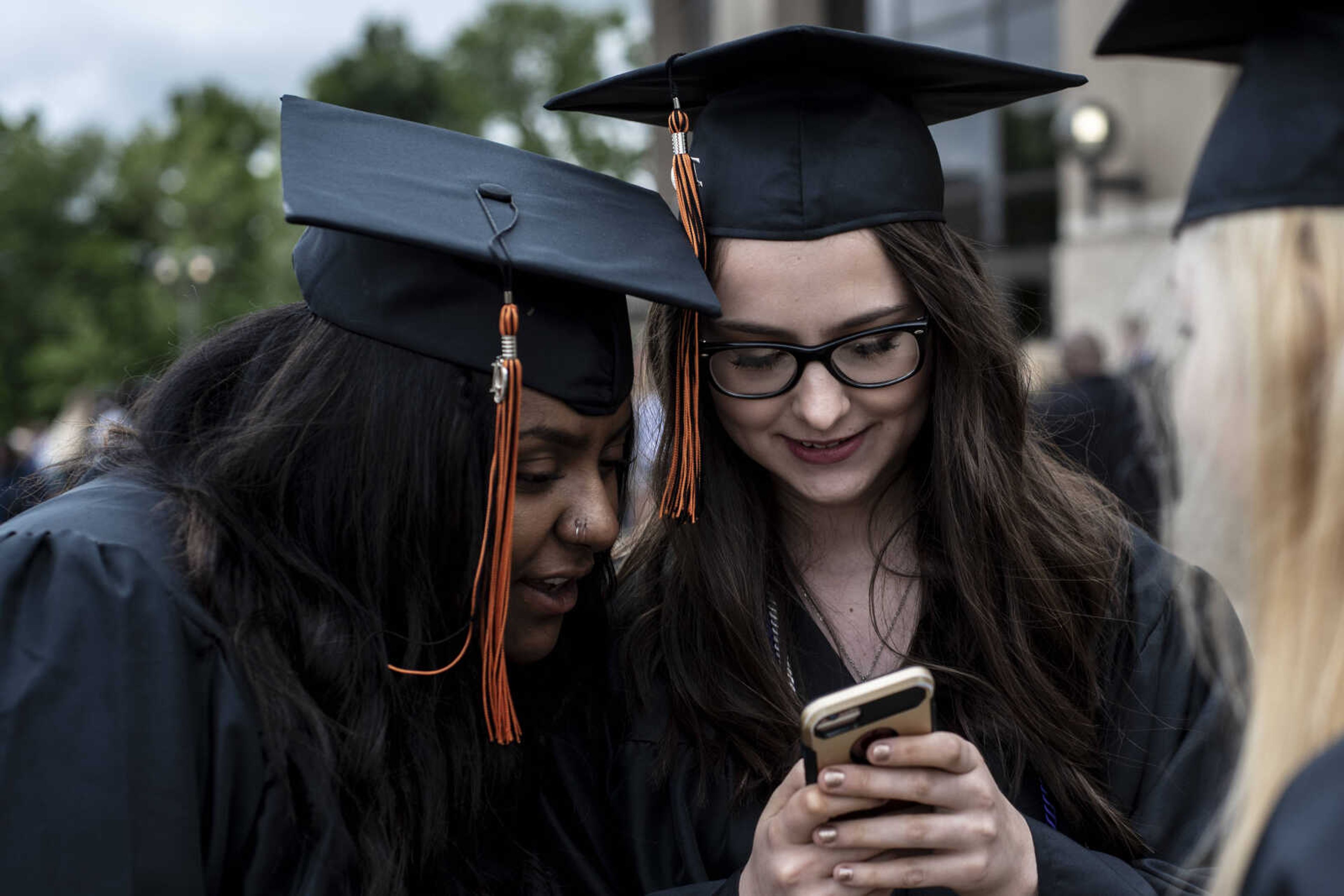 Emily Medlock, right, and her friend Taylor Driver look at a photo taken of the two of them before graduation at the Show Me Center Sunday, May 12, 2019, in Cape Girardeau.