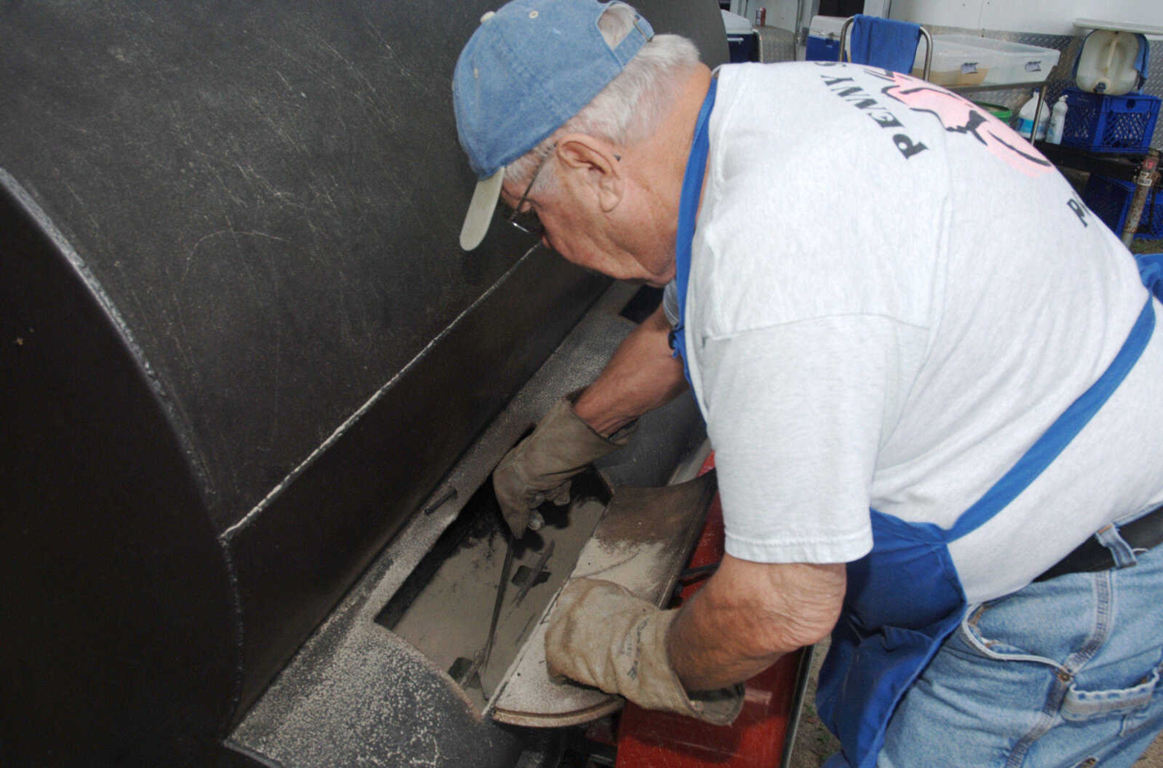 Reeder Withers of the Penny Street Porkers, cleans out the ashes from their grill at Saturday's, August 22, 2009, Cape BBQ Fest at Arena Park.