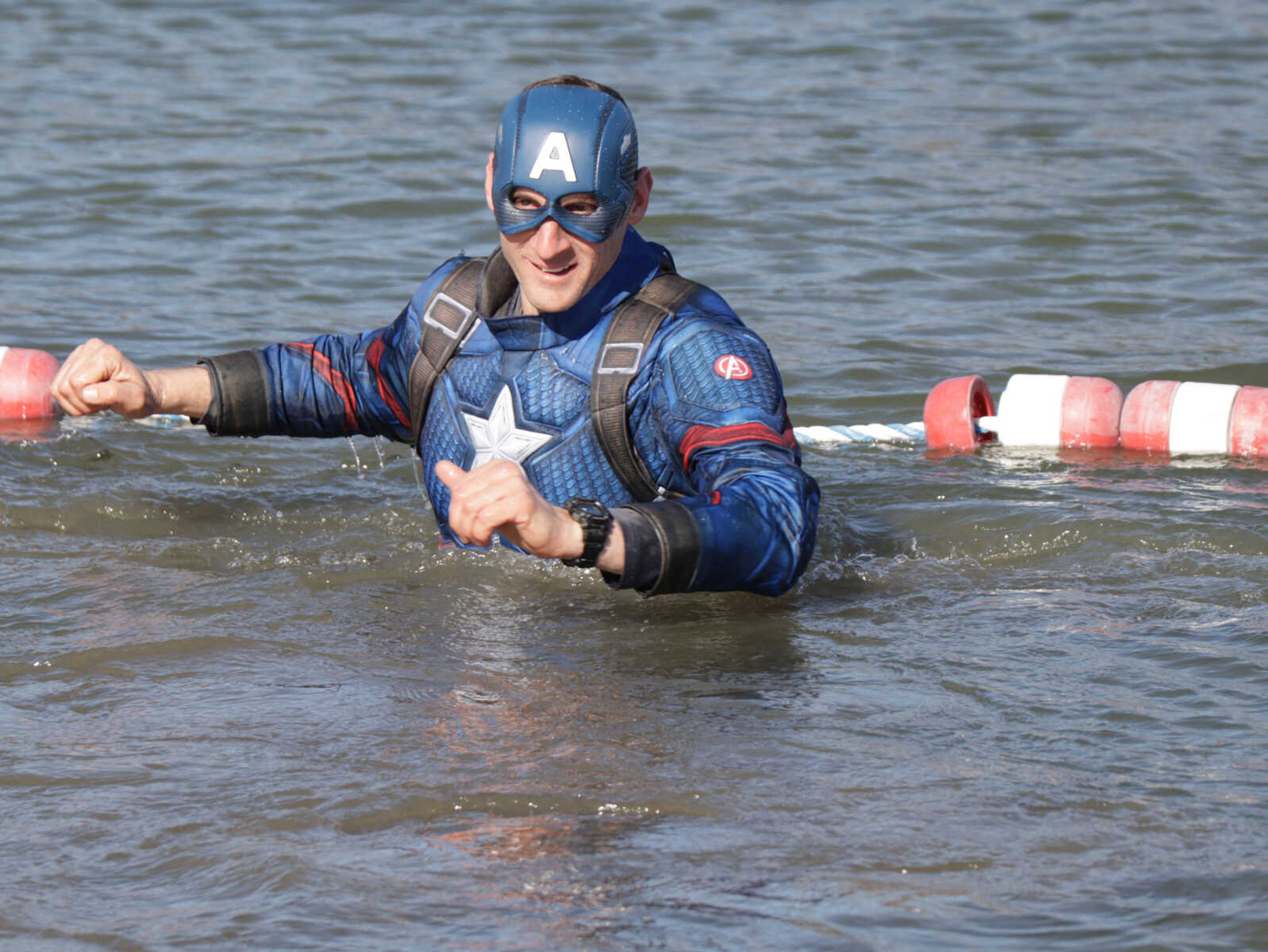 Diver dressed up as a superhero character working his way back  out of the water.