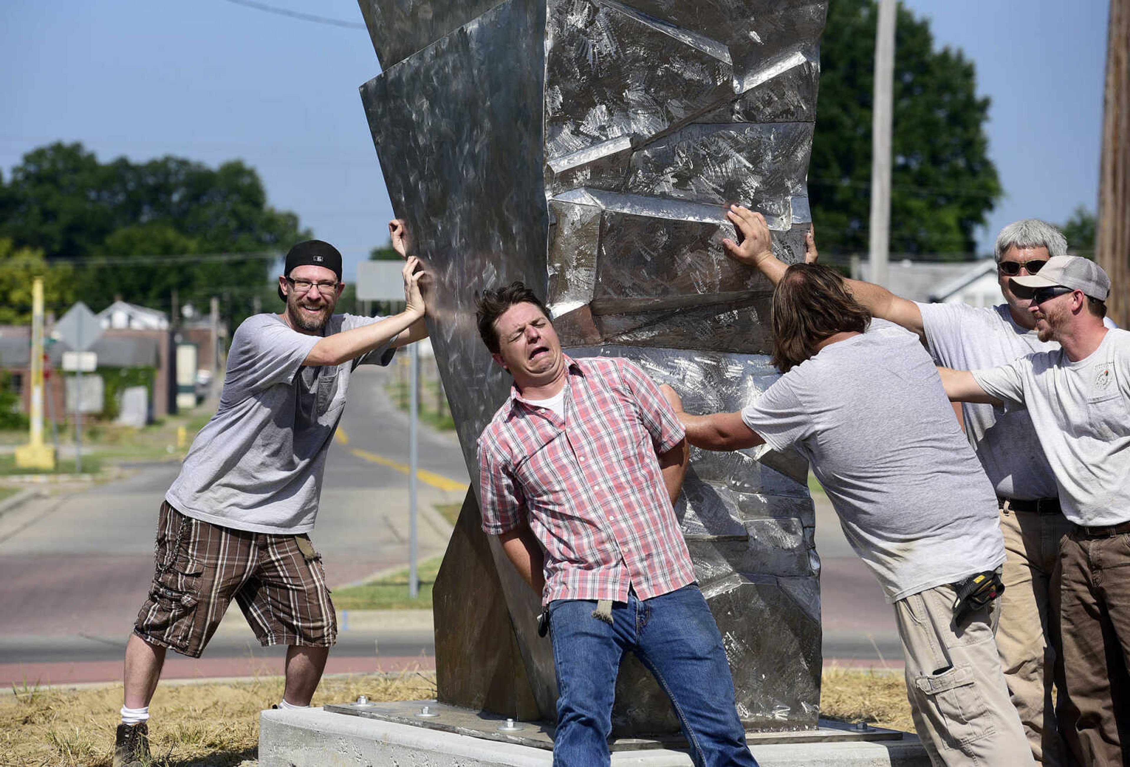 Chris Wubbena, left, and Cape Girardeau Parks and Recreation Department take a fun photo after the installation of Wubbena's 14-foot sculpture, "Commence", in the Fountain Street roundabout on Monday, July 24, 2017, near the River Campus.