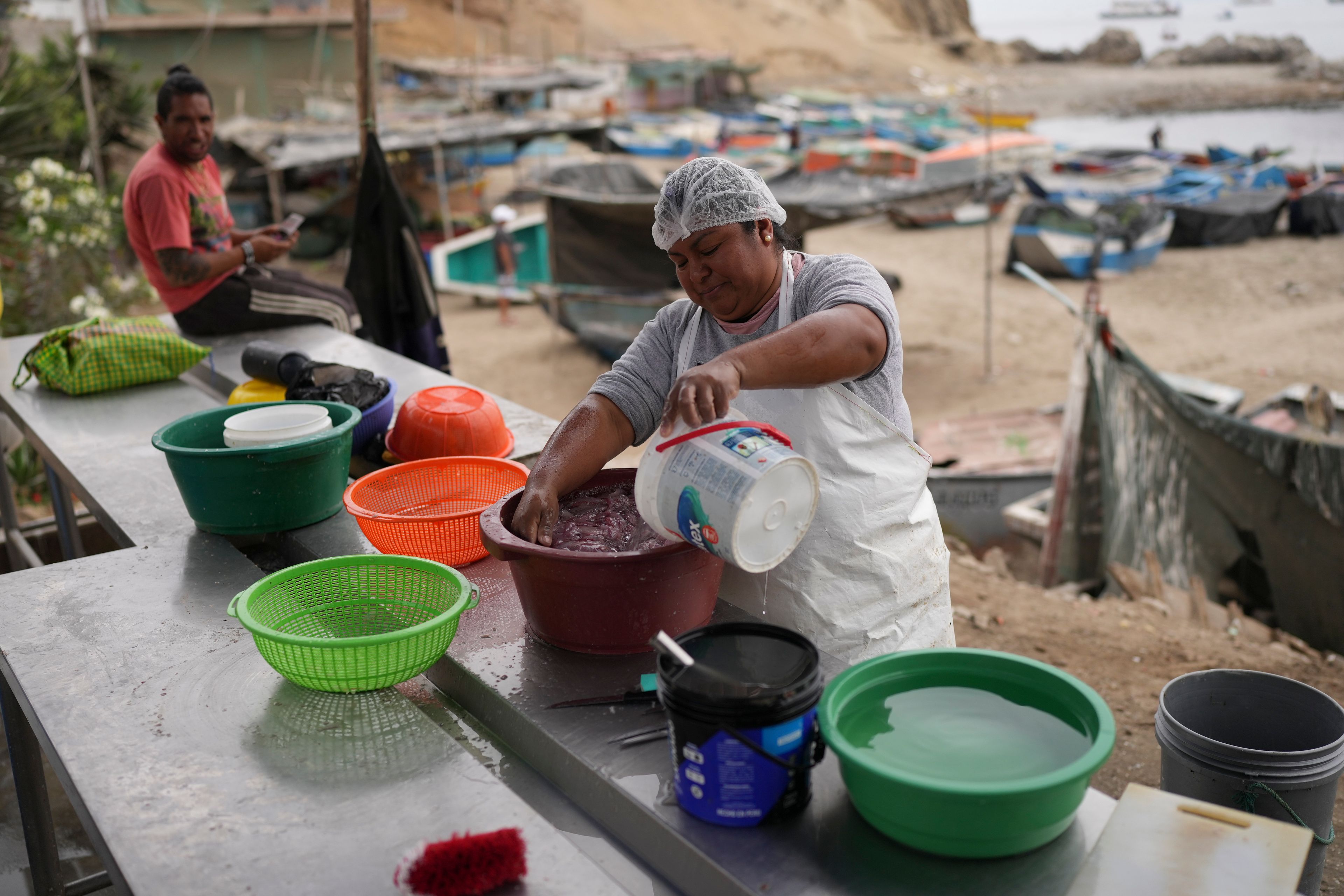 Vendor Rosa Collantes washes fish at a fish sales center near a Chinese-funded port construction in Chancay, Peru, Tuesday, Nov. 12, 2024. (AP Photo/Silvia Izquierdo)