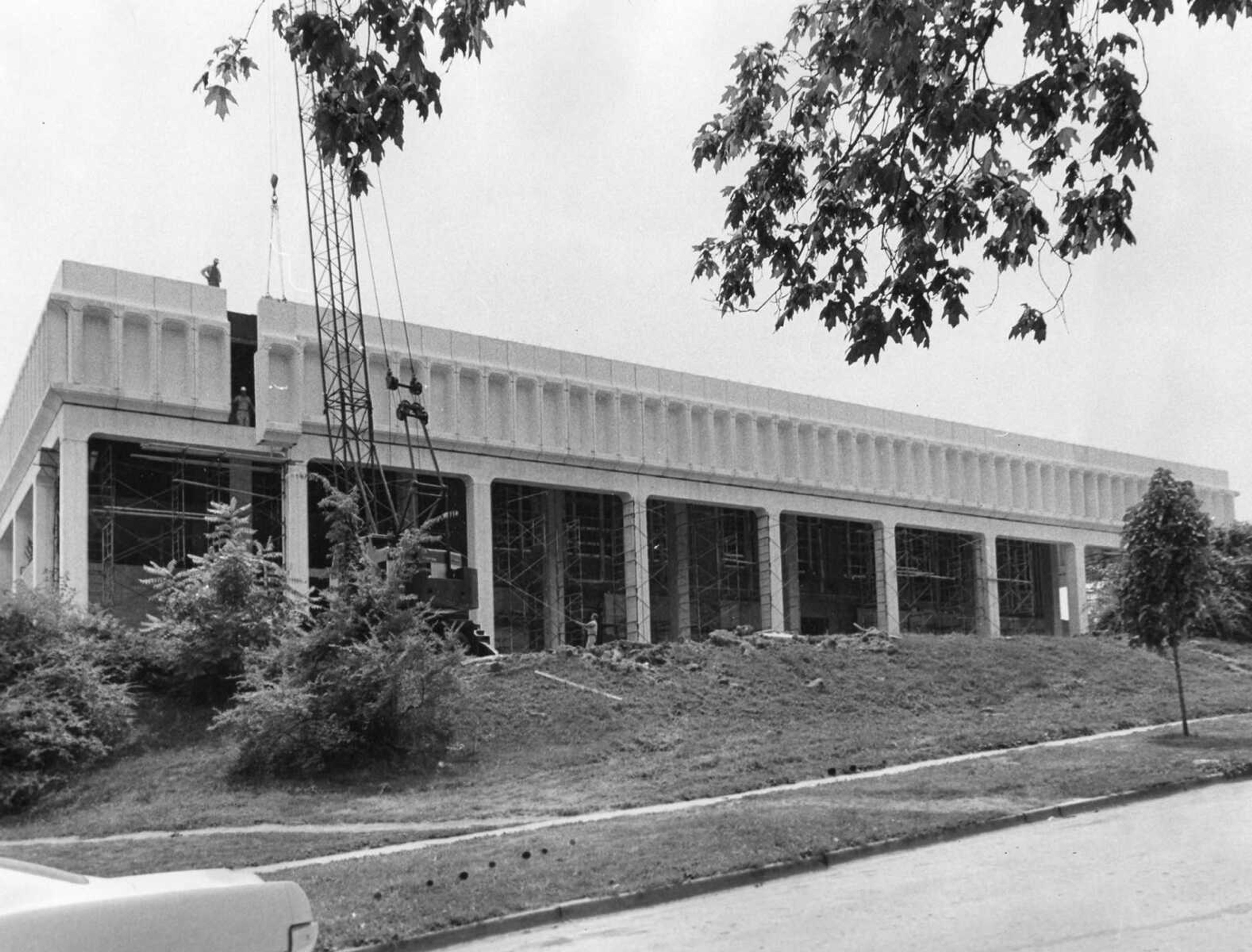 Published July 22, 1967
Like a missing tooth in otherwise perfect dental work, only the black gap marred the appearance of the new front to Kent Library before the final pre-cast stone was hoisted into place. The stone, one of 96 which went into the portico, weighs three tons, and here is being set in place by crane as workmen stand by to help guide it. Kent Library on the State College is undergoing a major expanson. (Southeast Missourian archive photo)