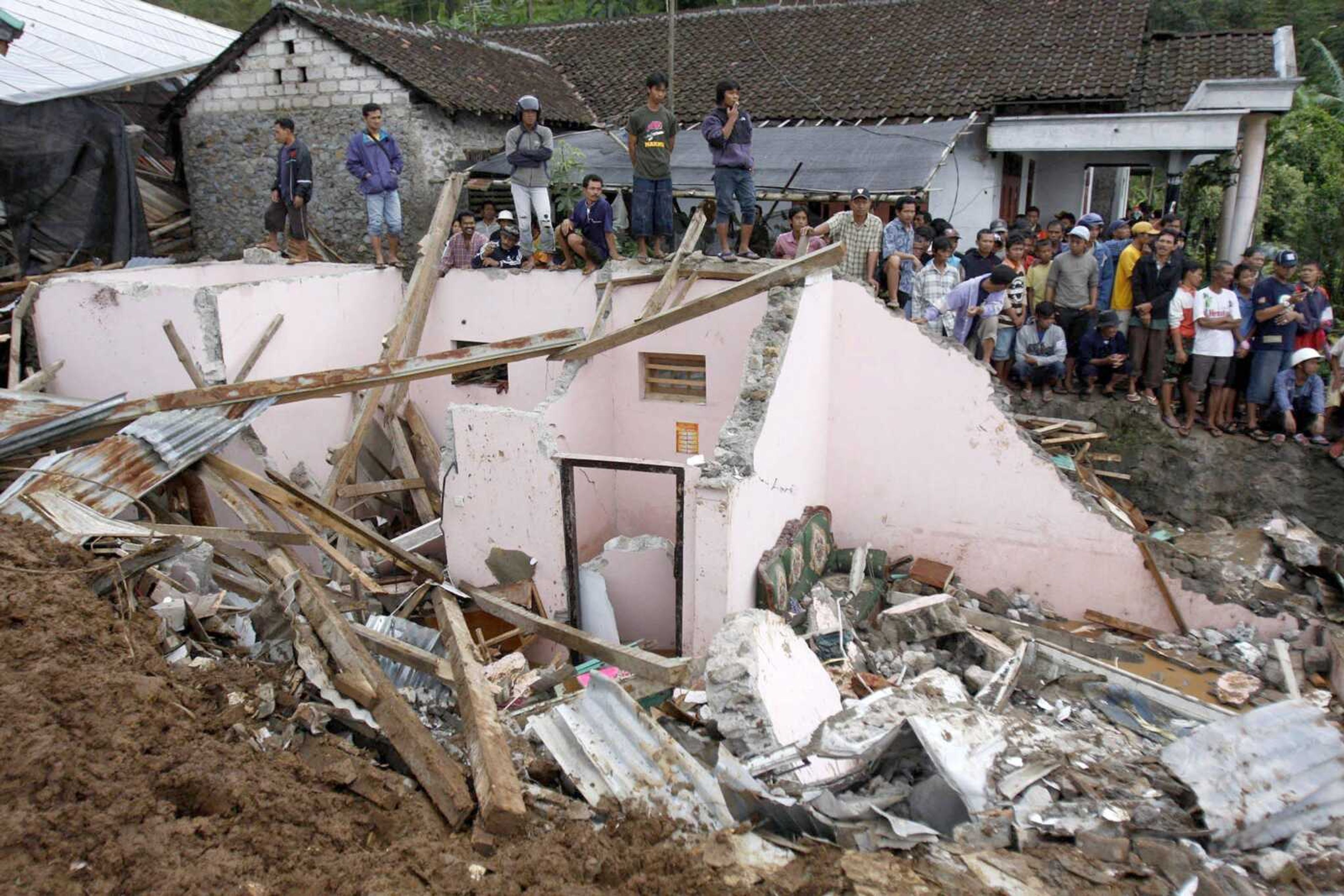 Residents stood Wednesday on the top of a house destroyed by landslide in Tawangmangu, Central Java, Indonesia. Days of torrential rain triggered landslides that killed at least 78 people. (Associated Press)