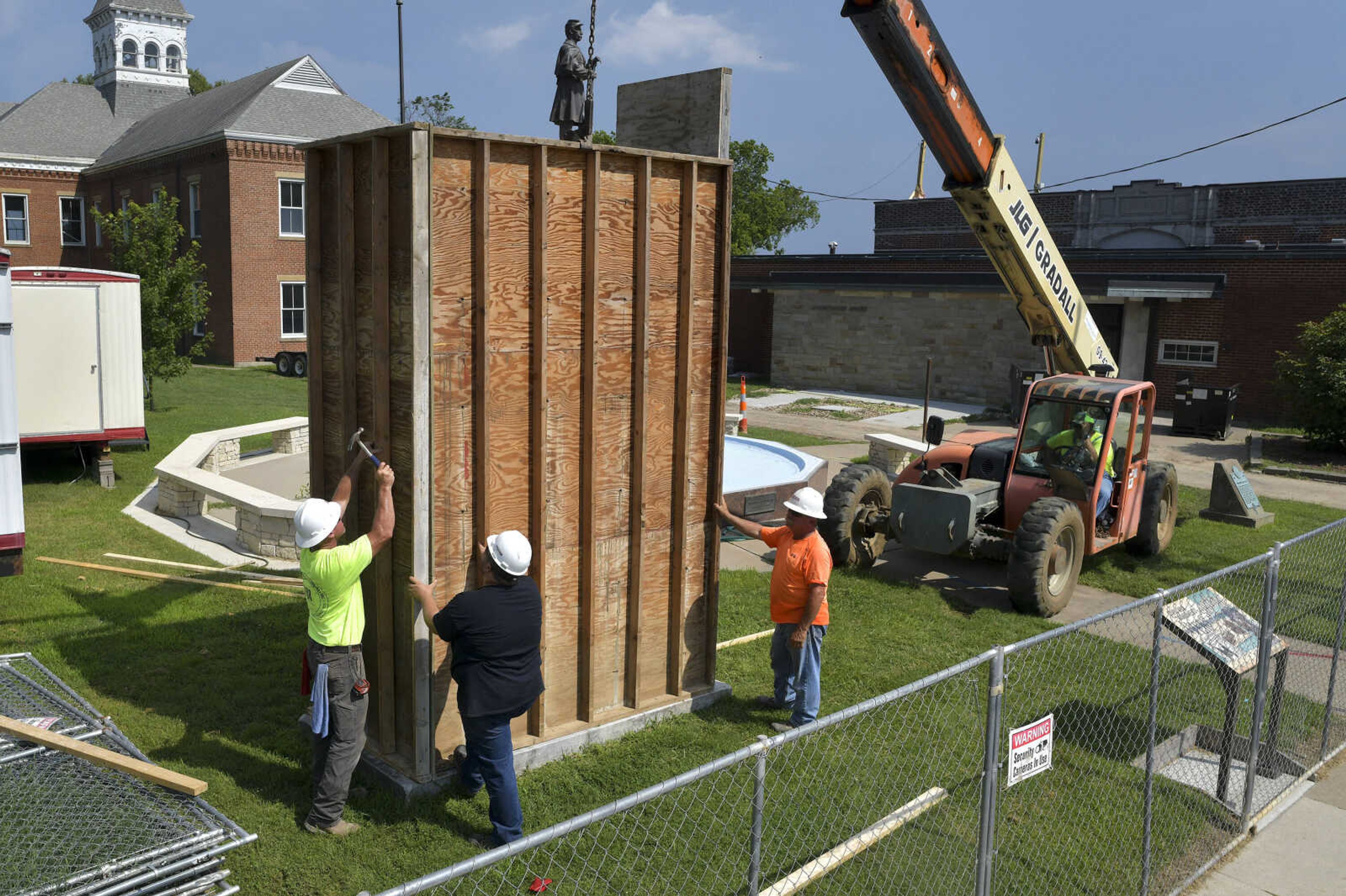 Construction workers nail down the final piece of a wooden box surrounding a Confederate States of America monument in Ivers Square on Tuesday, July 7, 2020, in Cape Girardeau.