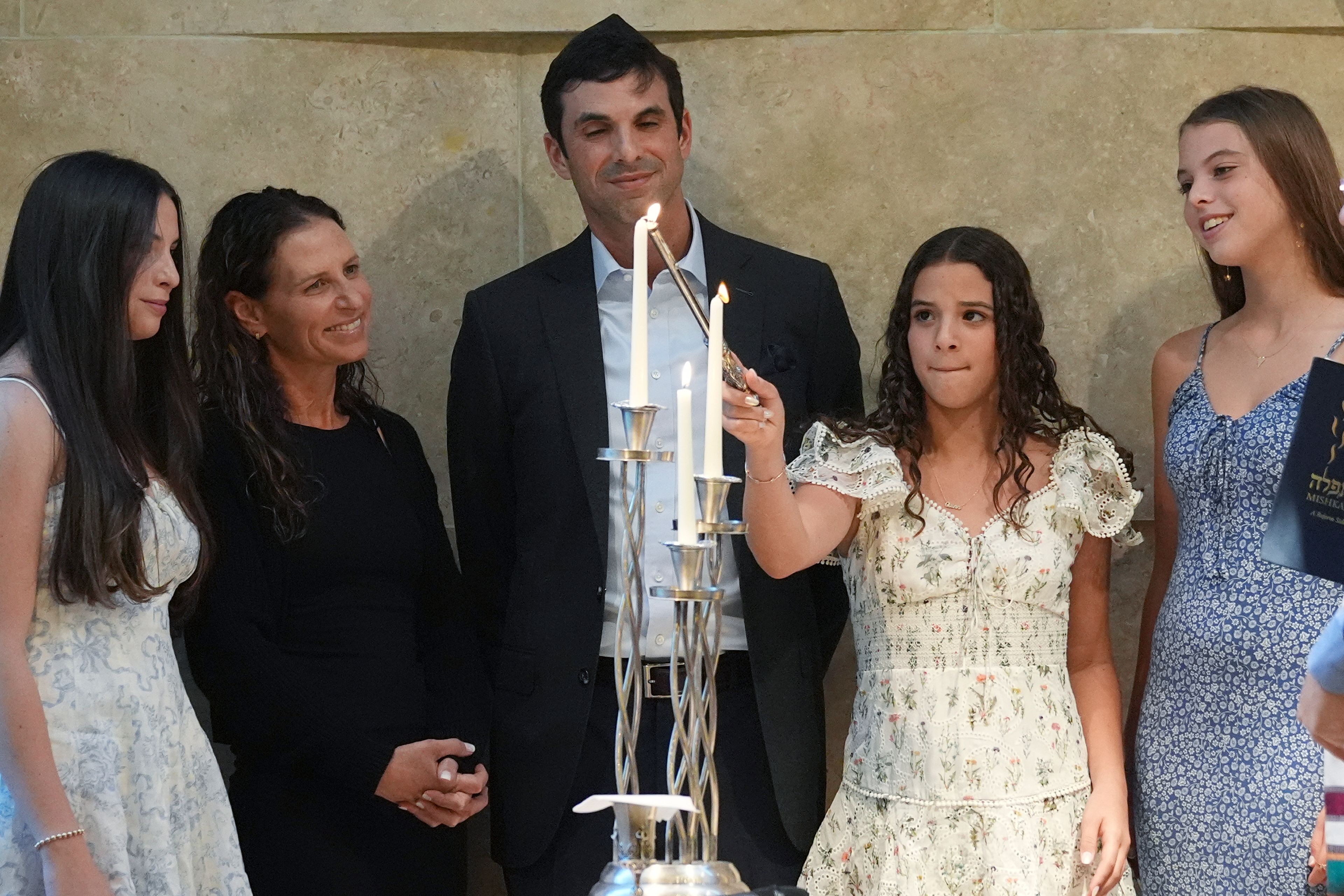 Quinn Schimel, second from left, lights a Shabbat candle as she stands with her family during a Shabbat service, Friday, Sept. 27, 2024, at Temple Beth Sholom in Miami Beach, Fla. (AP Photo/Wilfredo Lee)