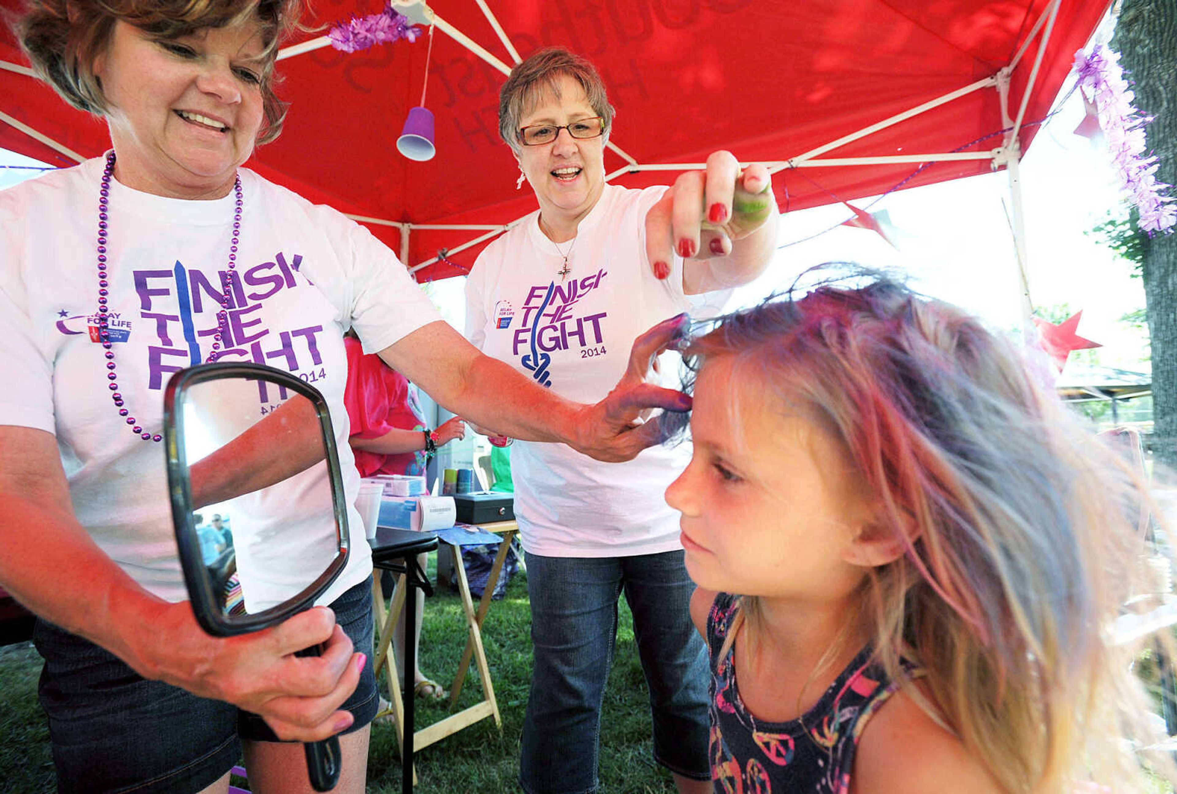 LAURA SIMON ~ lsimon@semissourian.com

Lisa Hemman, left, and Tammy Bohnert, center, put the finishing touches on Trinity Vandeven's new pink and blue hair style, Saturday, June 14, 2014, in the "Warriors of Hope" tent during the Relay for Life of Cape Girardeau County fundraiser at Arena Park.