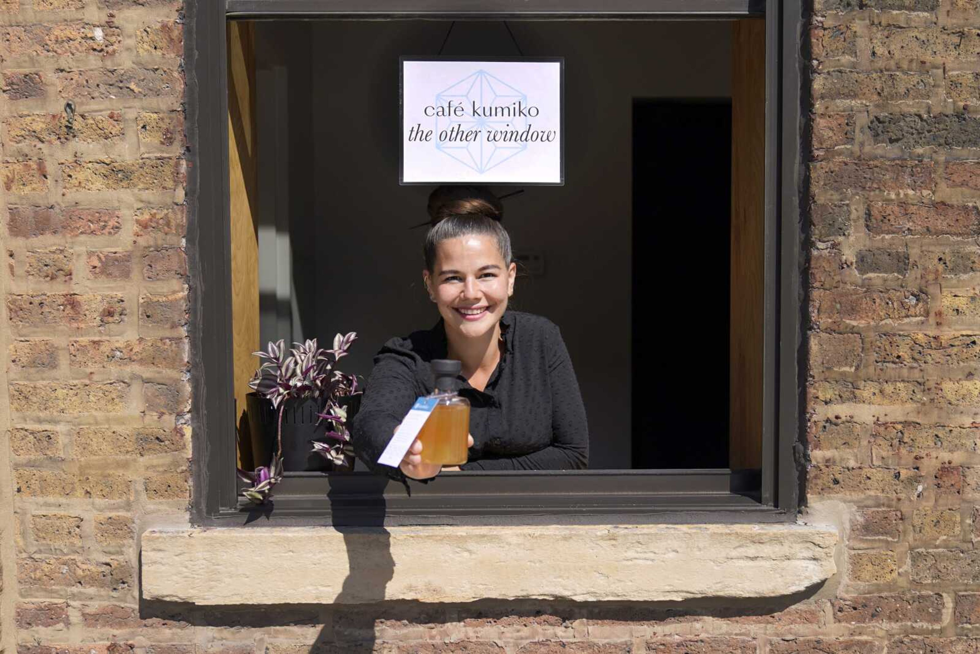 Julie Momosa poses for a portrait at the serving window with a "cocktail to go" at the Kumiko bar in Chicago's West Loop neighborhood Aug. 14. Momosa, a longtime bartender and co-owner of Kumiko, shut the bar on March 16 due to the pandemic, spending the next three months collecting petition signatures and lobbying the city to allow cocktails to go. That measure passed June 17, and she sold the first to-go cocktail in Chicago that day.