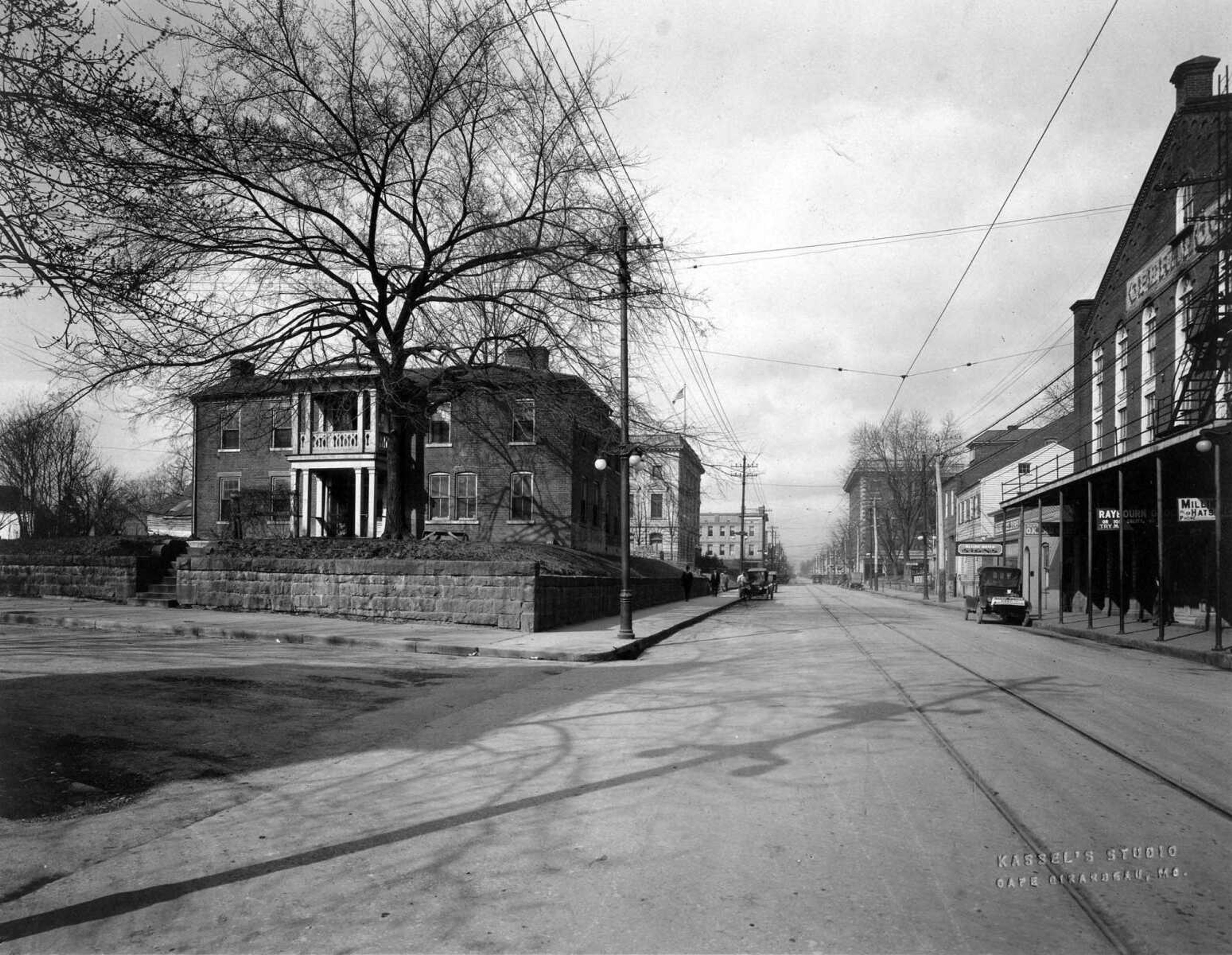 It was 1923 and there was no need for parking meters on Broadway. Only four or five automobiles can be seen in this photo made, the shadows show, in the forenoon. About this time the Naeters knew they had again outgrown their quarters and the plans were forming for a new building. The decision focused on this corner, and on Sept. 11, 1925, the present Missourian Building was dedicated, one of the most modern plants of its day. Its site: the location above, with the old house razed to make way. Behind it is the Federal Building and across the street the Old Opera House where The Missourian had its beginning. (Kassel's Studio photo; published 10-2-1965, anniversary edition)