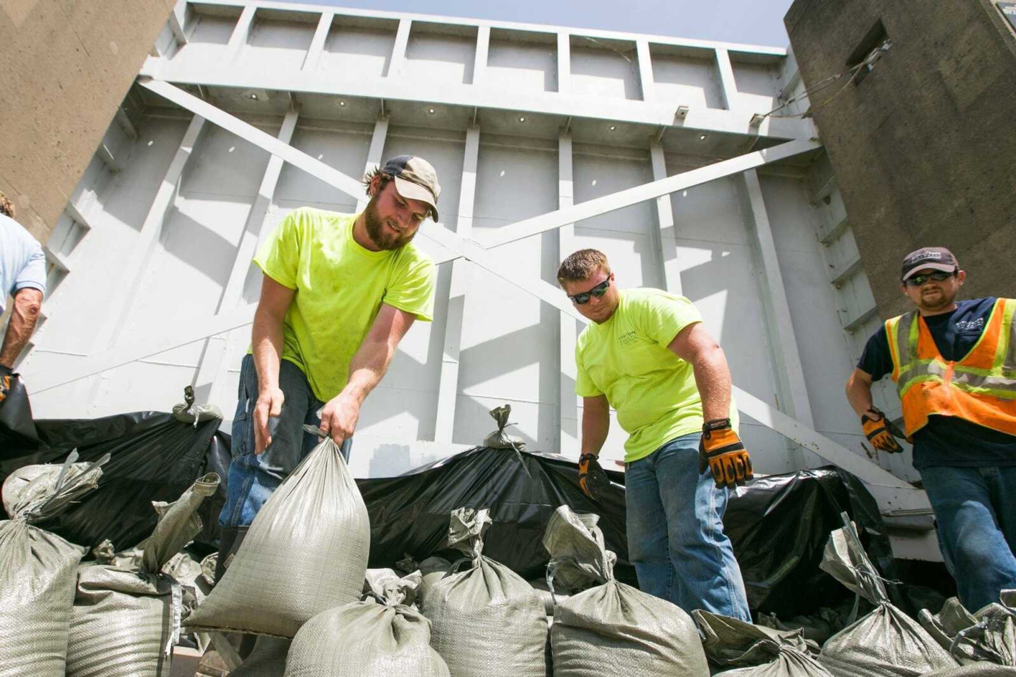 Chris Menz, Josh James and Robert Medlin with Cape Girardeau Public Works department storm water division place sandbags at the base of the Themis Street floodwall entrance after closing it Wednesday afternoon. The Themis Street gate is closed by the time the Mississippi River hits 35 feet while the Broadway gate is closed at 37.5 feet. (Glenn Landberg)