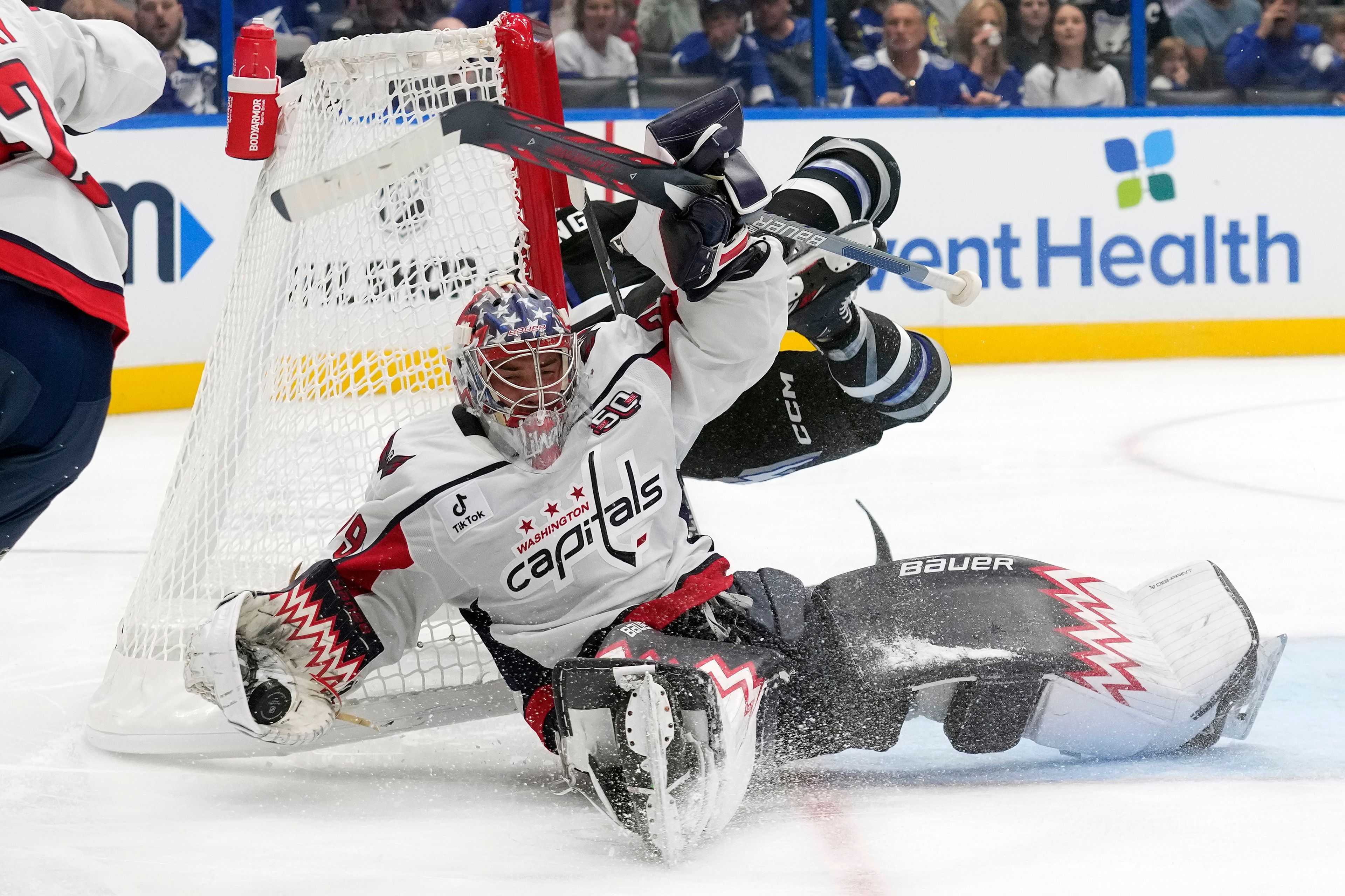 Washington Capitals goaltender Charlie Lindgren (79) makes a save as he gets knocked over by Tampa Bay Lightning center Luke Glendening during the second period of an NHL hockey game Saturday, Oct. 26, 2024, in Tampa, Fla. (AP Photo/Chris O'Meara)